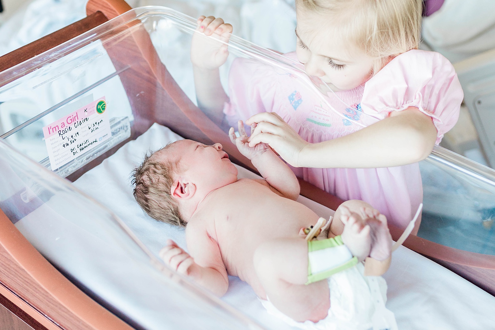 Big sister meeting baby sister for first time by Fresh 48 Photographer, Caitlyn Motycka Photography