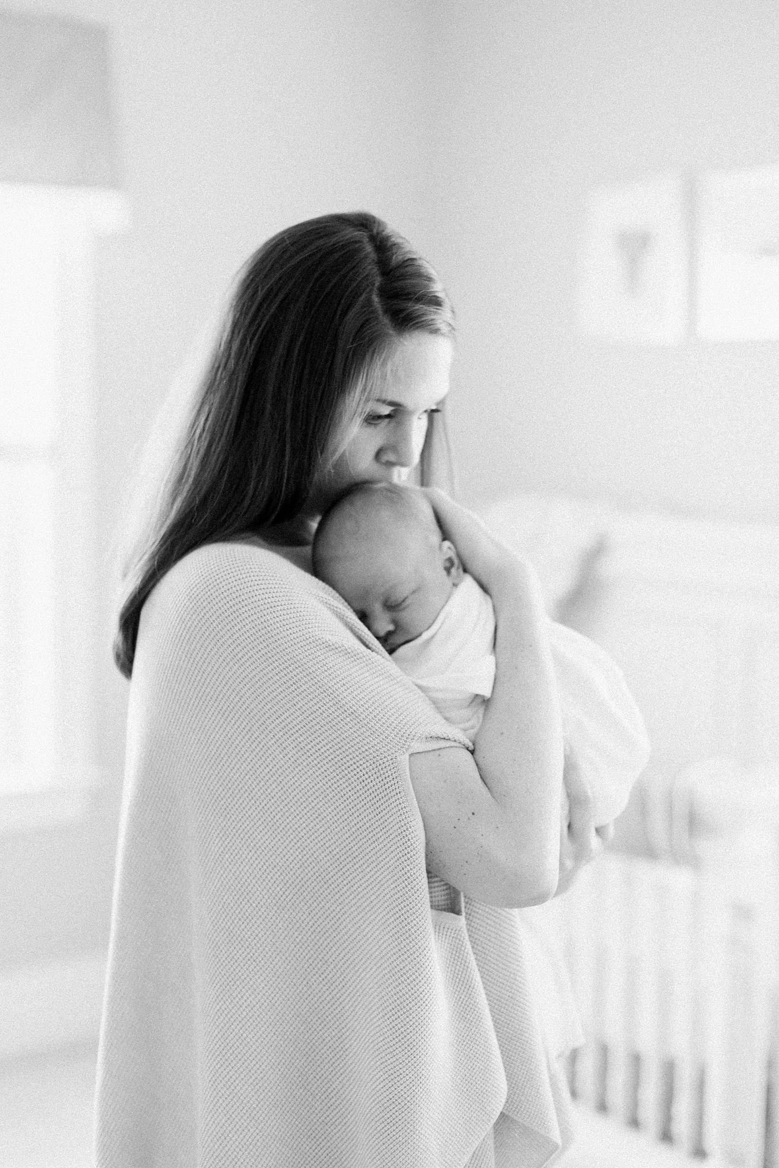Black and white image of mom holding baby by Charleston lifestyle newborn photographer, Caitlyn Motycka Photography