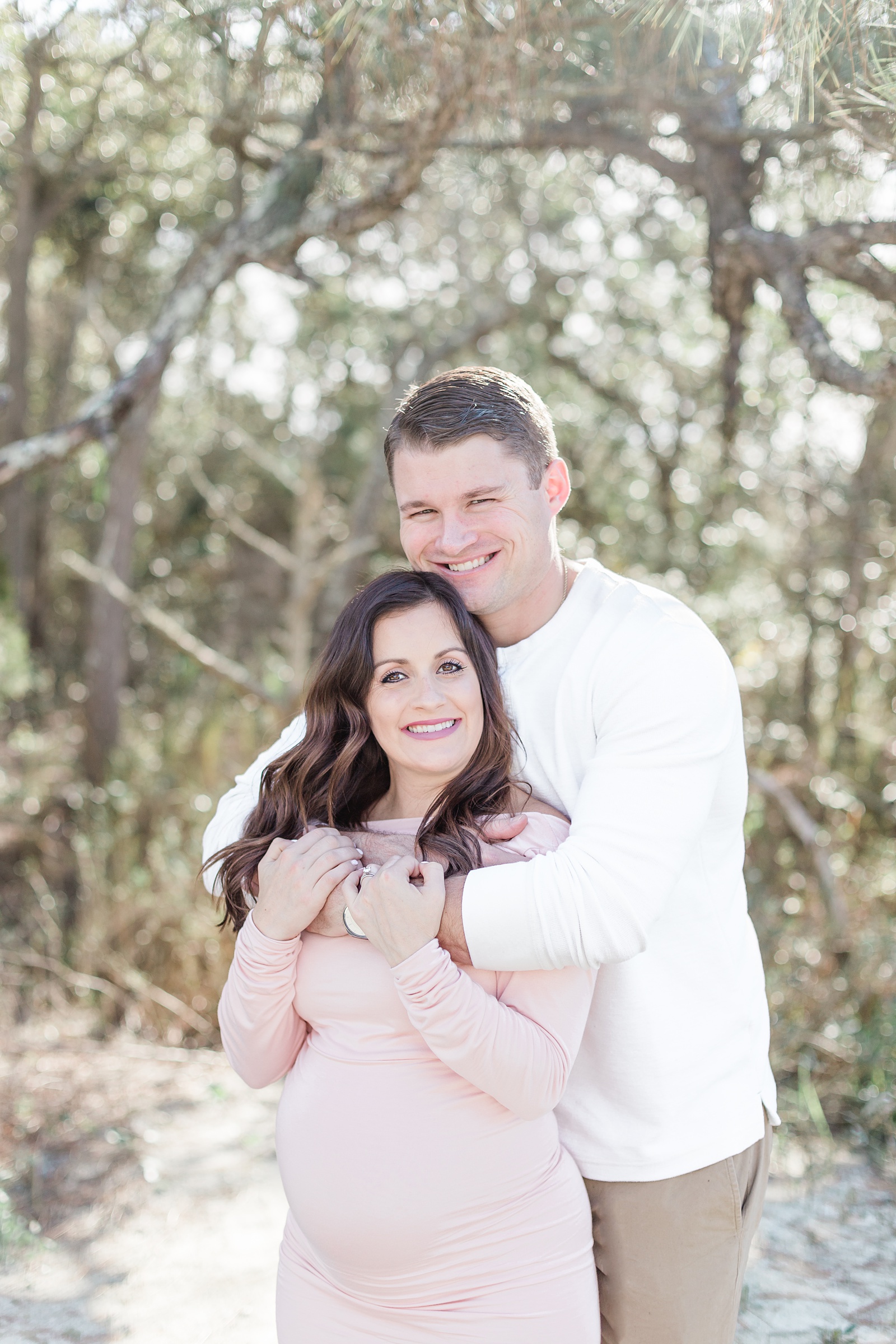 Couple hugging on Folly Beach during maternity session by Caitlyn Motycka Photography