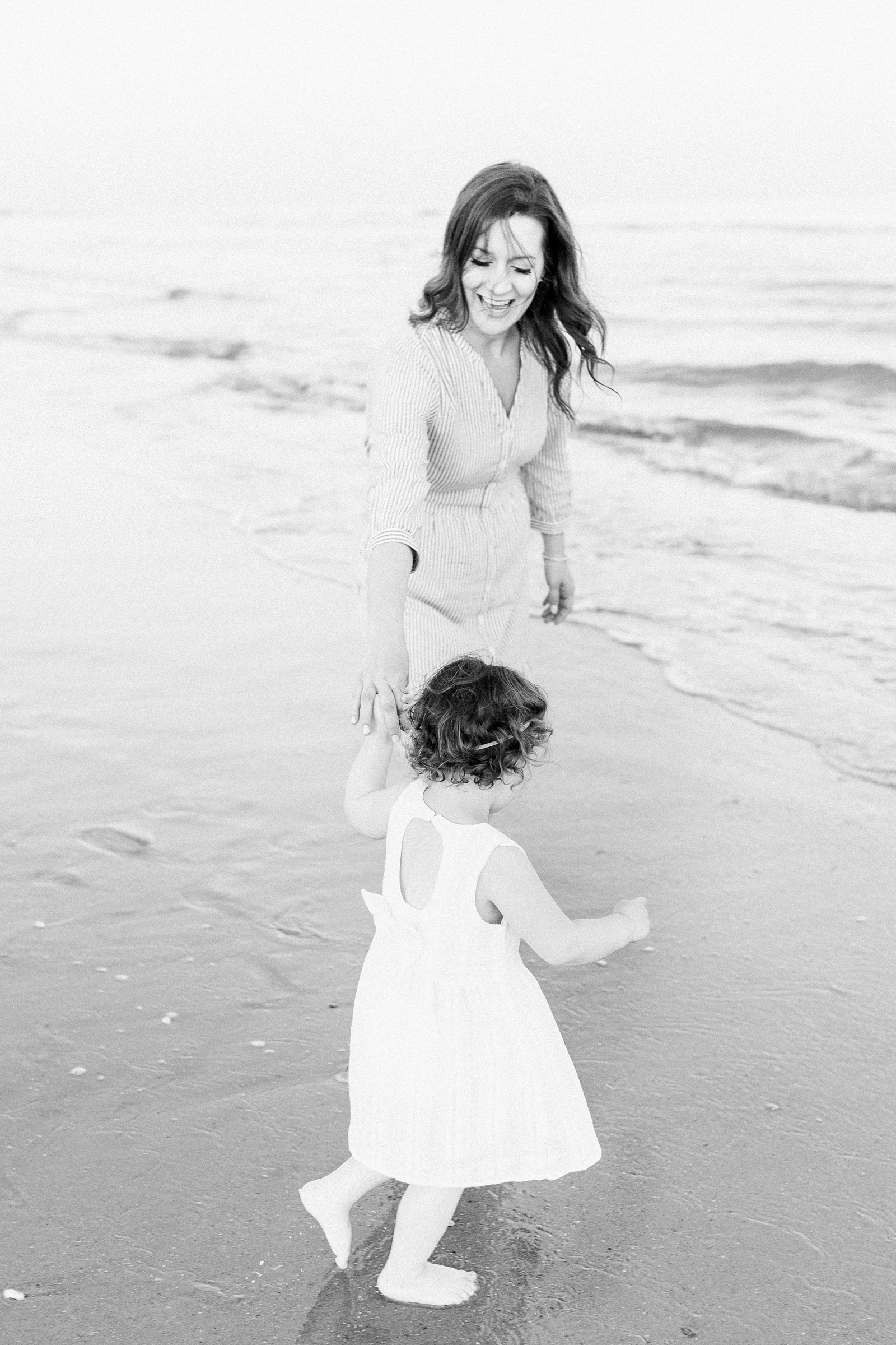Black and white image of mom and daughter playing in the water on Isle of Palms beach | Caitlyn Motycka Photography