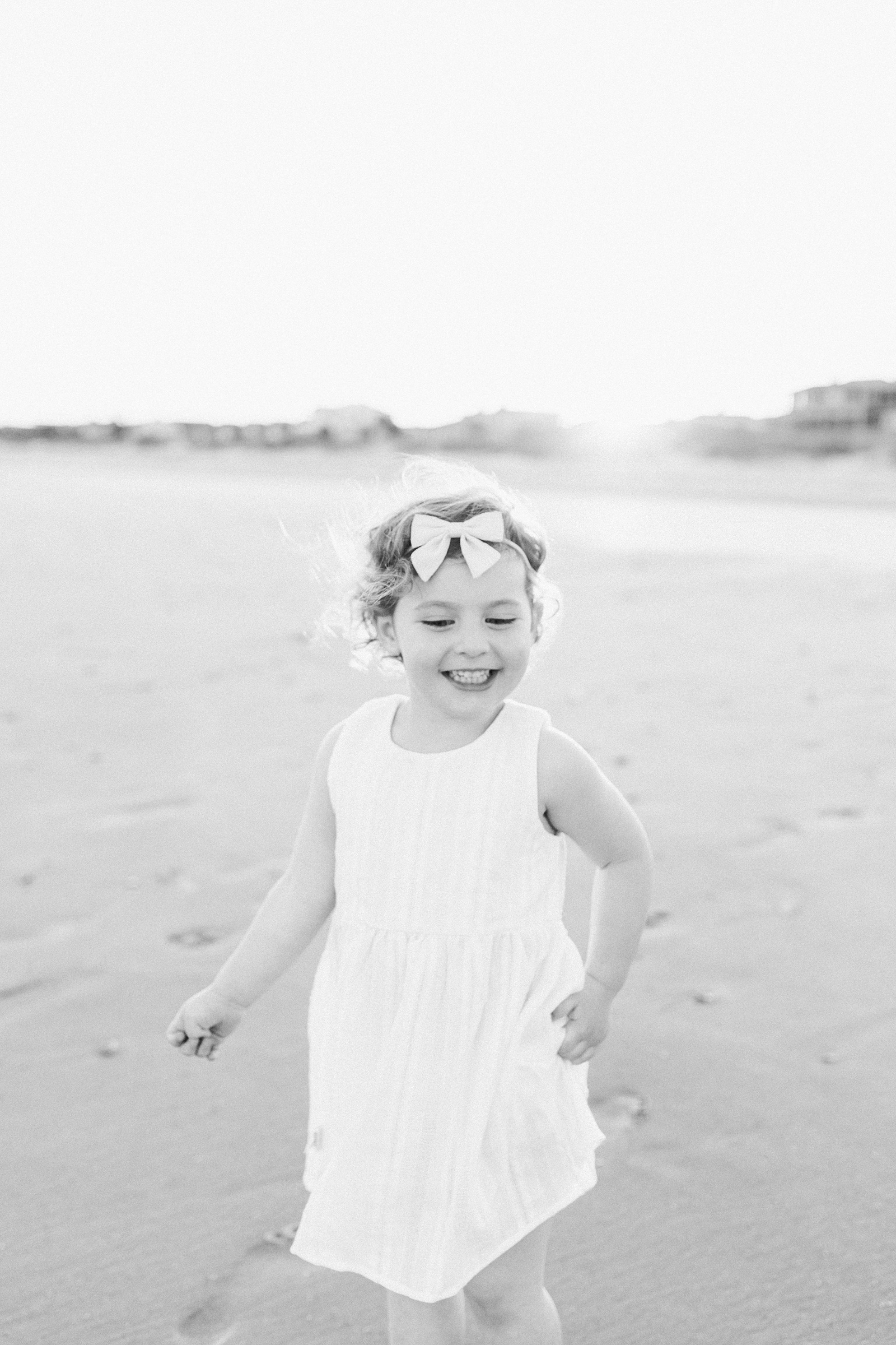 Black and white image of girl playing on beach by Charleston Extended Family Photographer, Caitlyn Motycka Photography