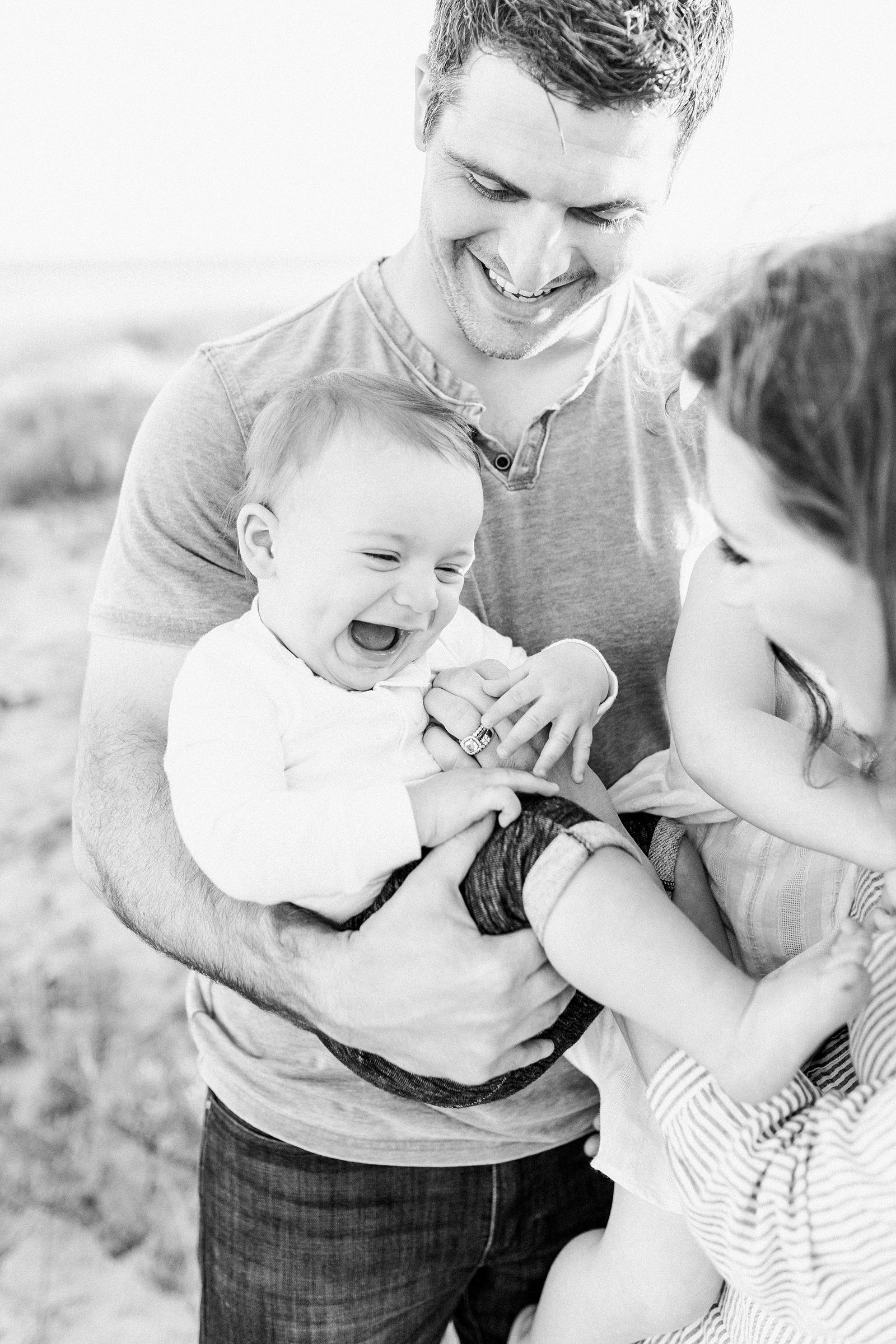 Black and white candid photo of baby boy with family by Caitlyn Motycka Photography