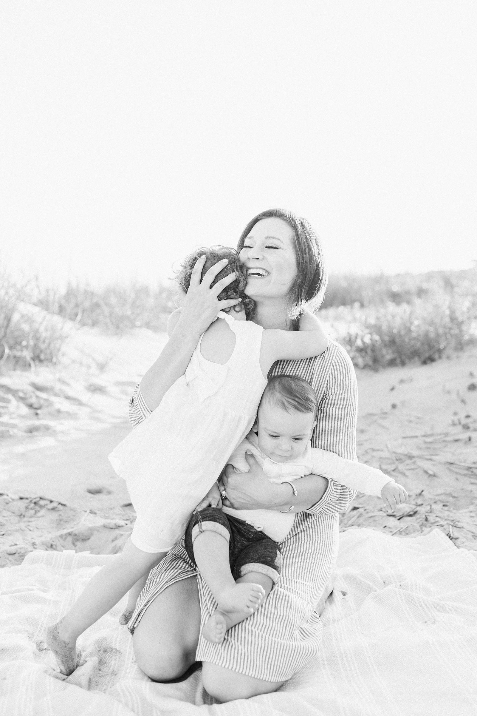 Candid photo of mom embracing her babies during family session by Caitlyn Motycka Photography