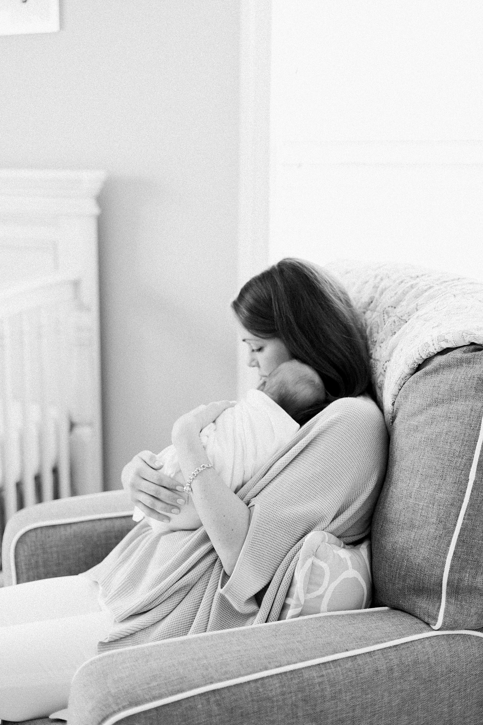Black and White image of mom rocking baby in nursery by Charleston Newborn Photographer, Caitlyn Motycka Photography