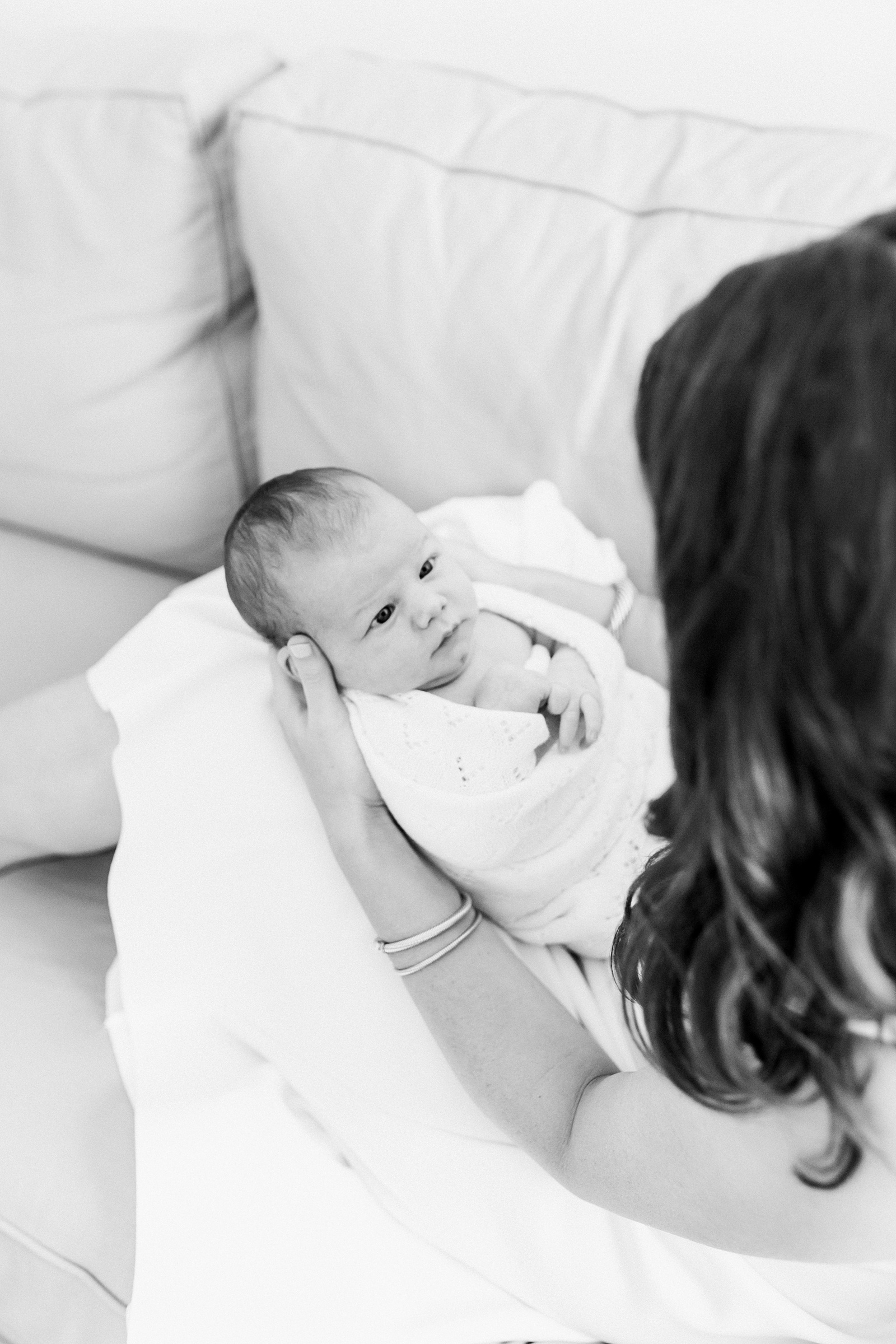 Black and white image of mom with newborn on sofa by Charleston Newborn Photographer, Caitlyn Motycka Photography