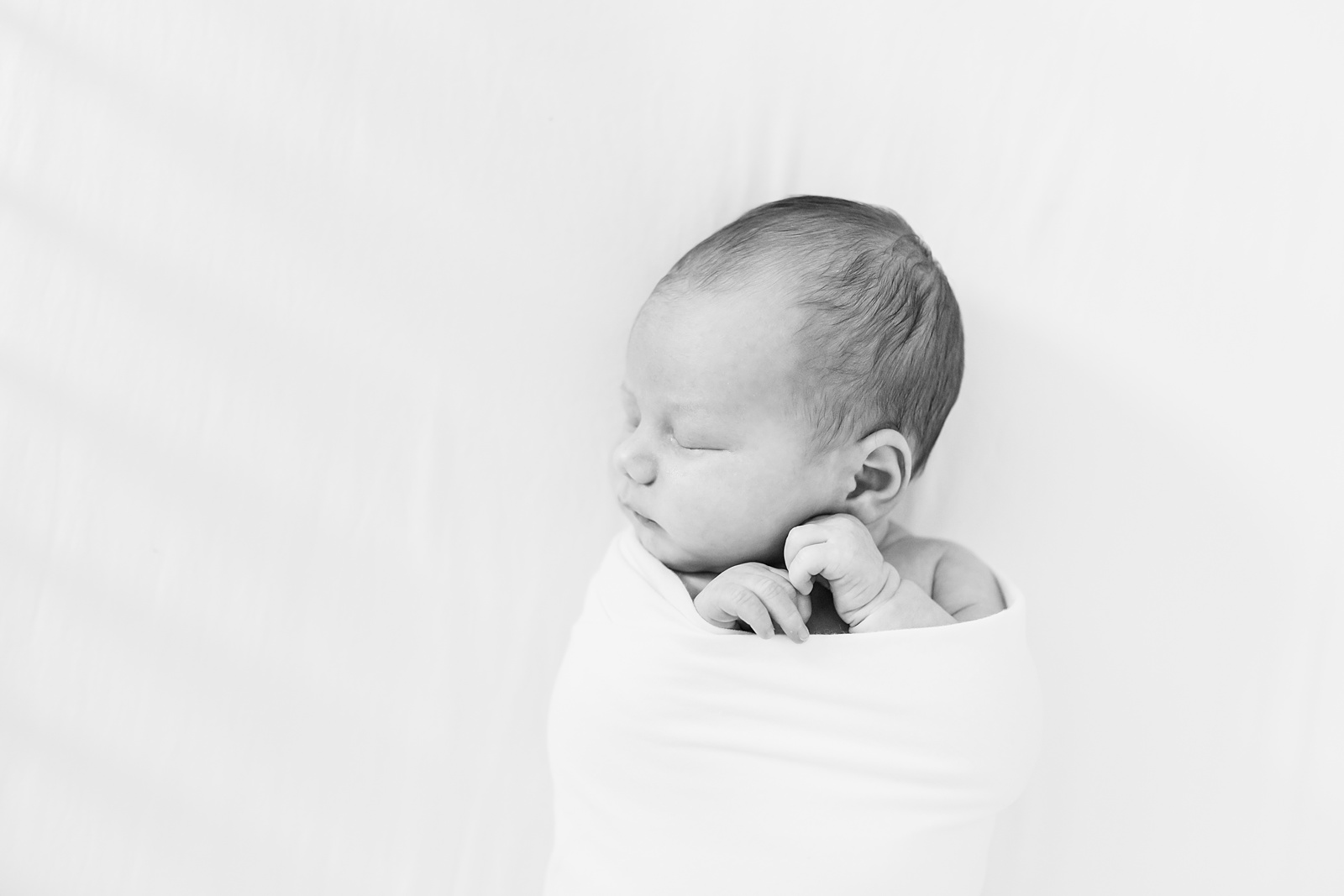 Baby in swaddle during lifestyle newborn photography session by Caitlyn Motycka Photography
