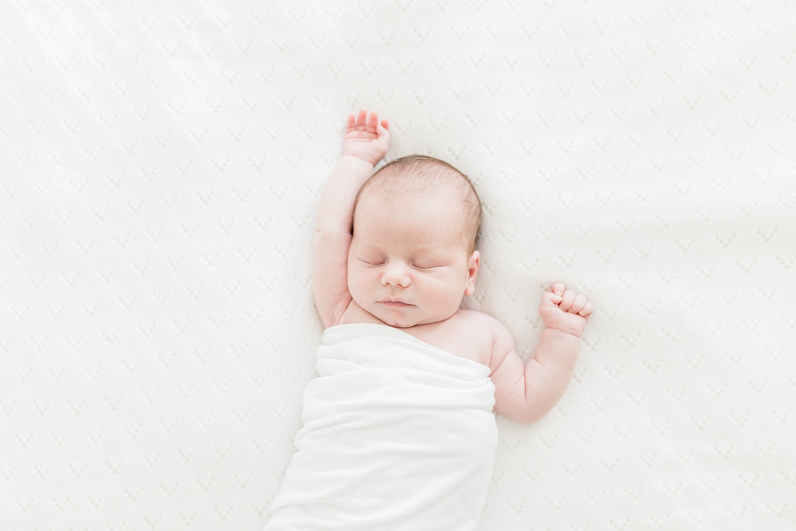 Baby in relaxed swaddle during lifestyle newborn photography session by Caitlyn Motycka Photography