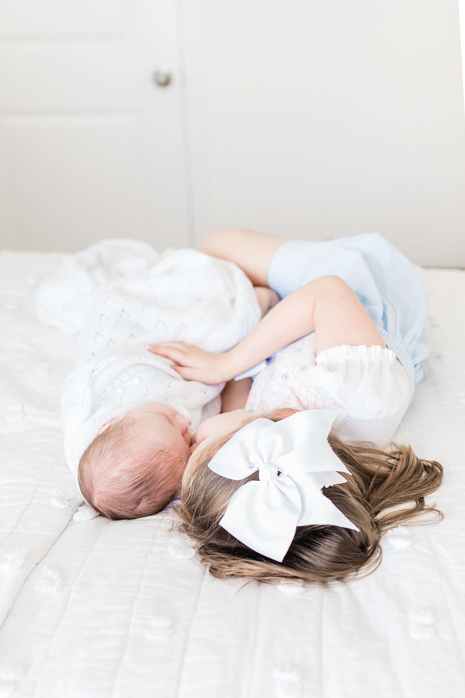 Siblings on bed during newborn session by Caitlyn Motycka Photography