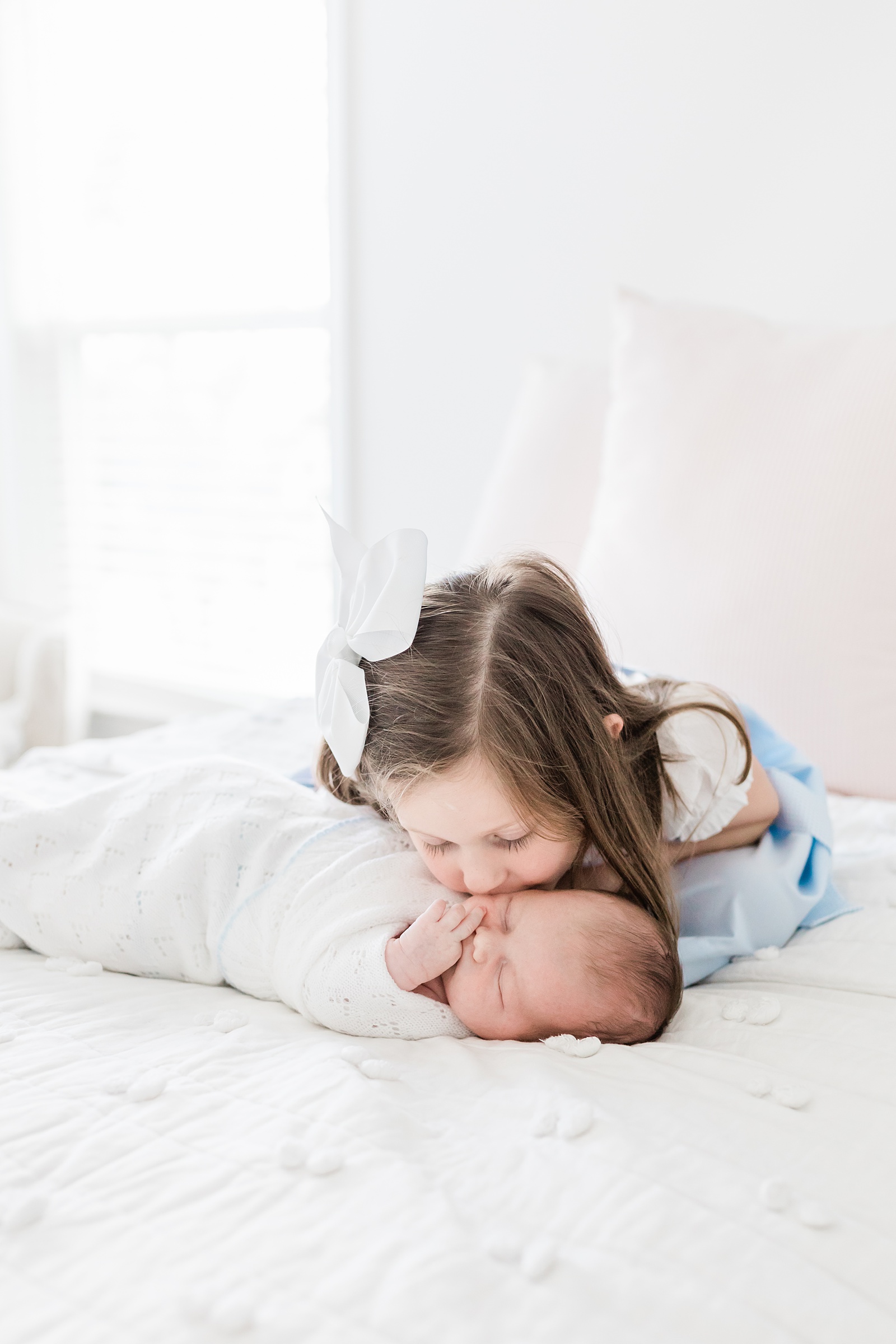 Big sister on bed with newborn by Caitlyn Motycka Photography