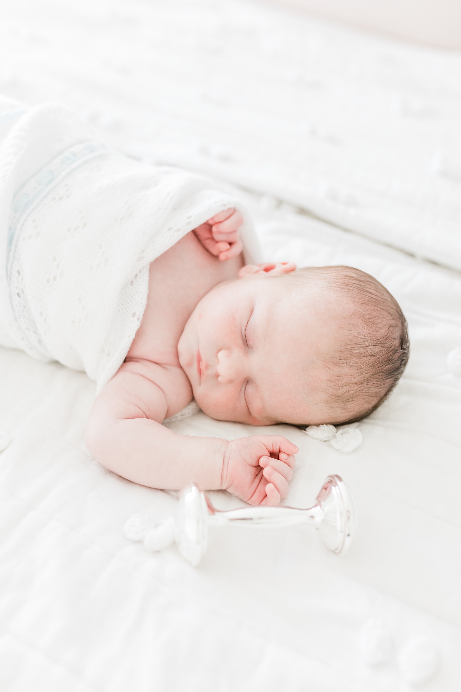 Baby boy sleeping in Feltman Brother's blanket with rattle by Caitlyn Motycka Photography