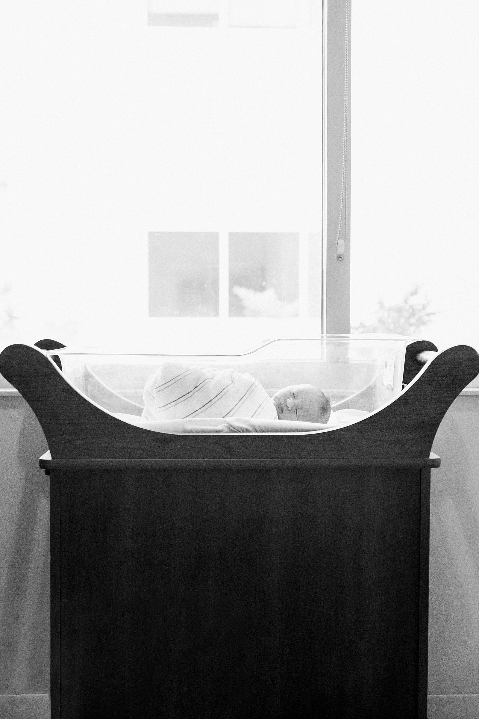 Black and white image of baby in hospital bassinet by Caitlyn Motycka Photography