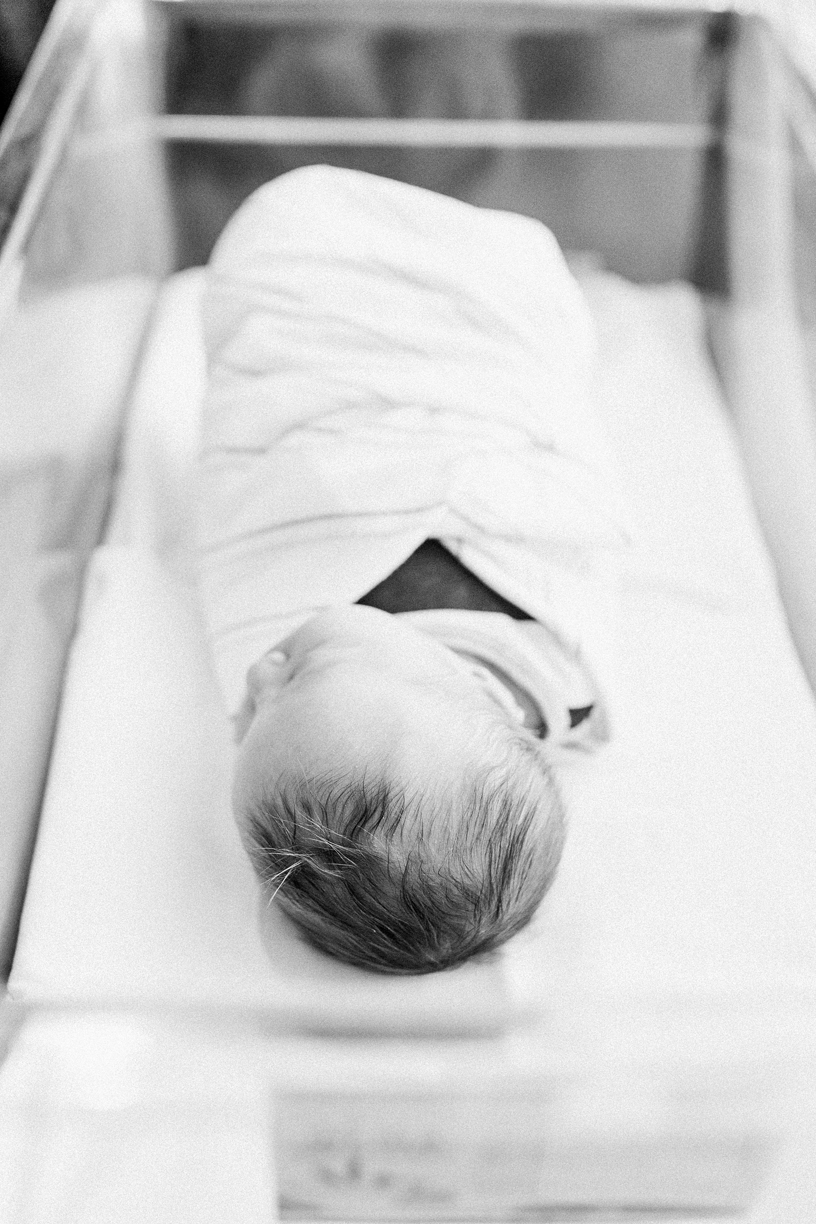 Black and white image of newborn in hospital bassinet | Caitlyn Motycka Photography