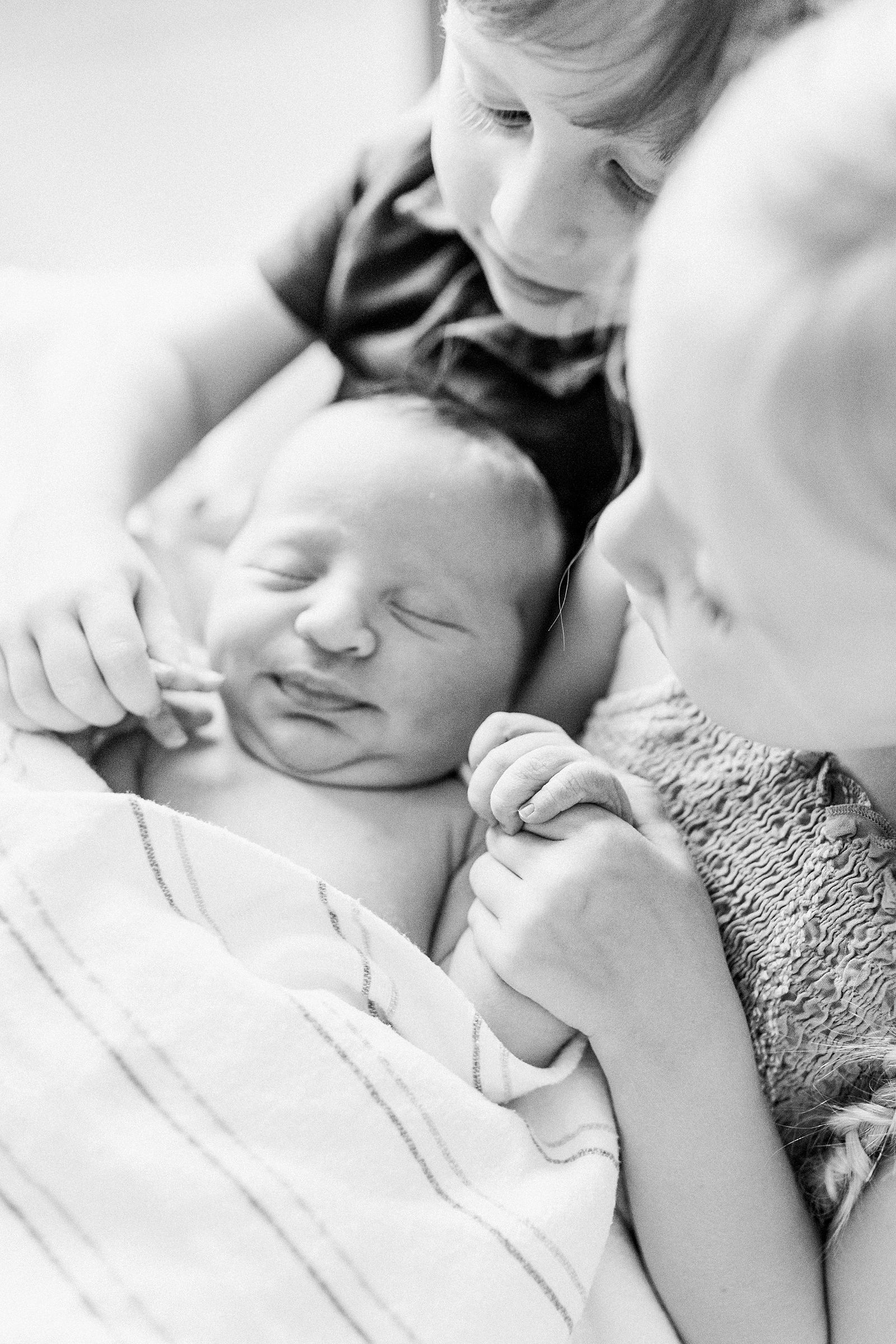 Black and white image of siblings holding baby during Fresh 48 session | Caitlyn Motycka Photography