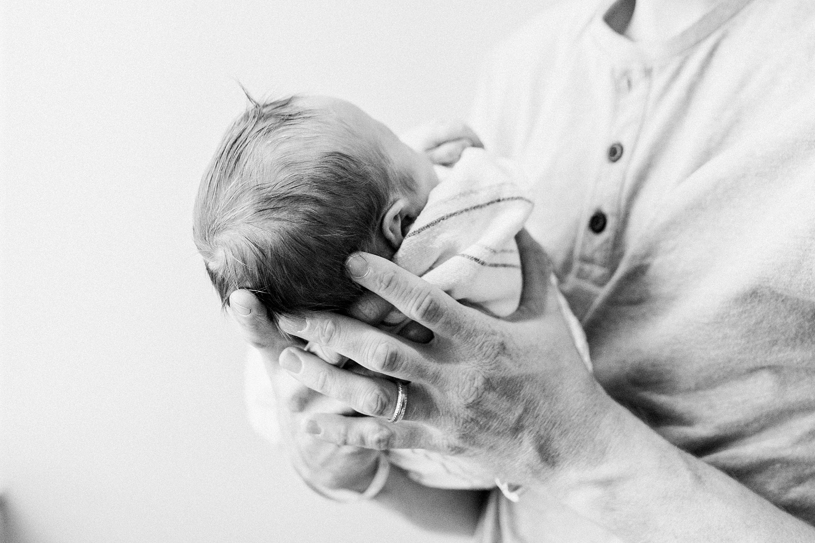 Black and white image of Dad holding baby in hospital | Caitlyn Motycka Photography