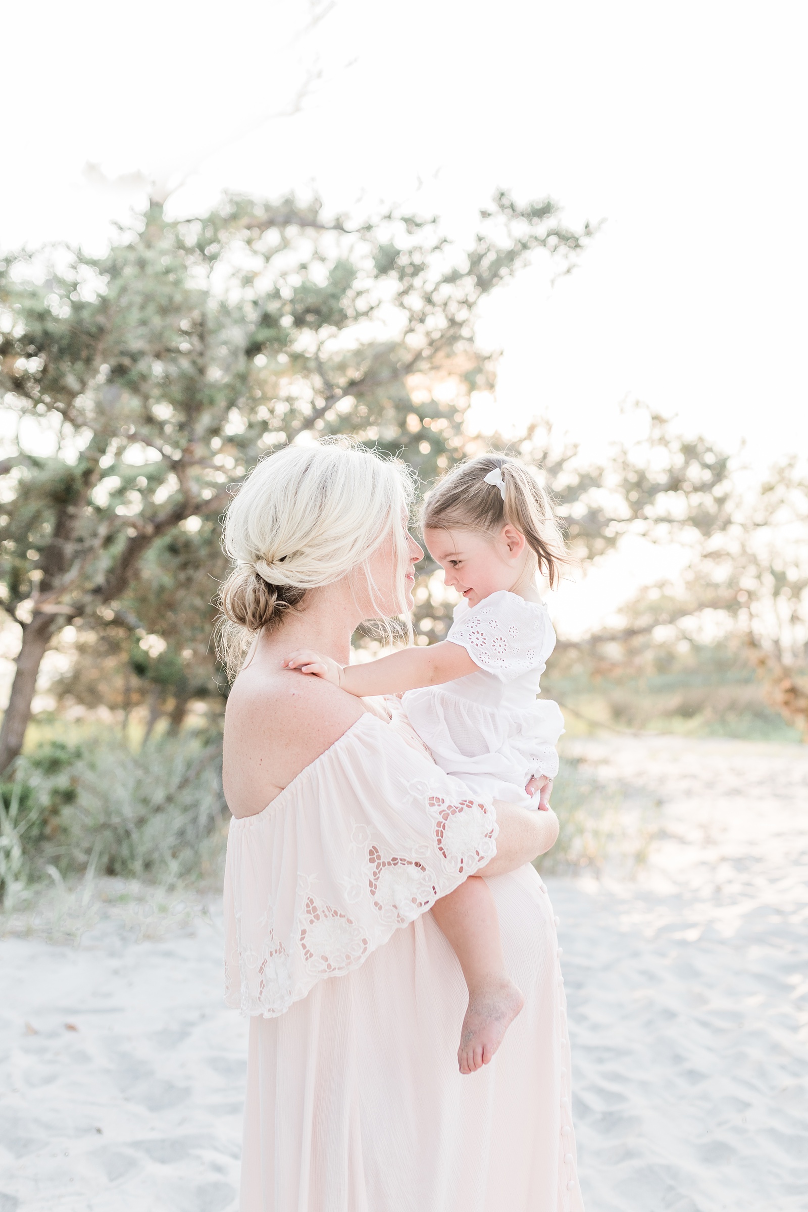 Mom with daughter sitting on bump during maternity session by Caitlyn Motycka Photography