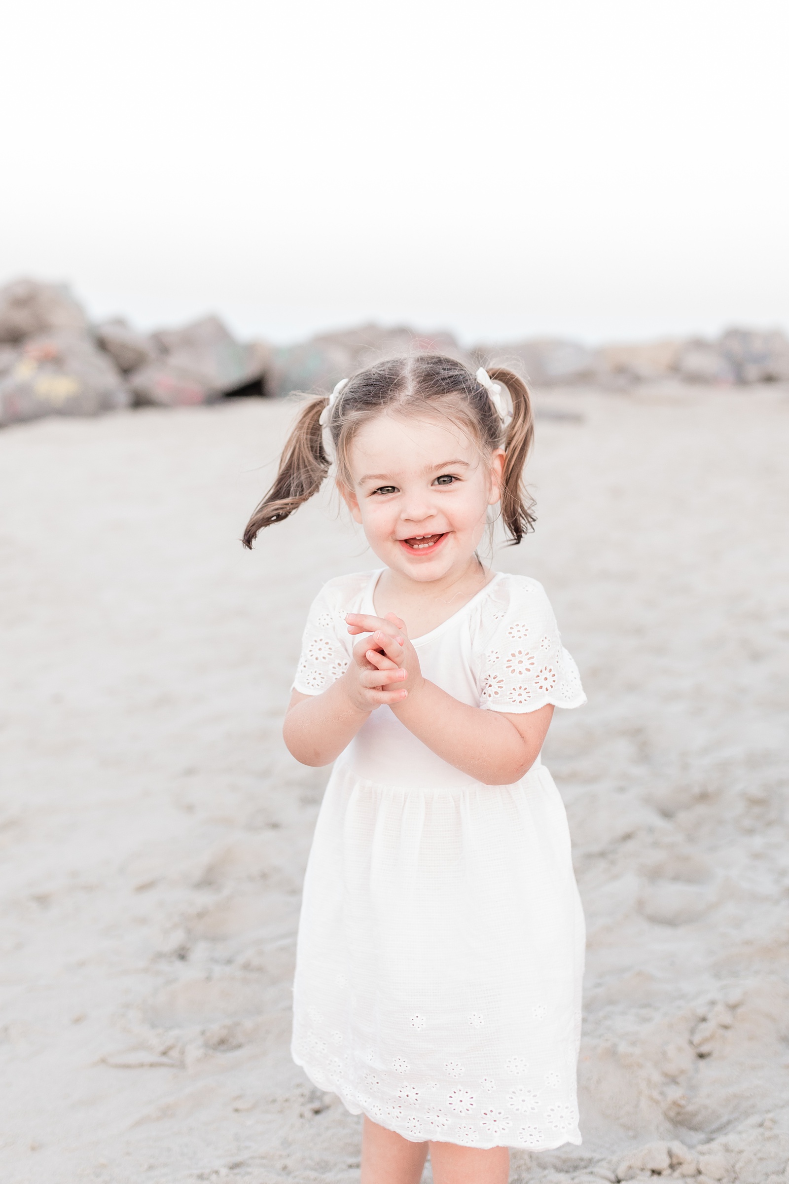 Toddler girl in white eyelet dress on Folly Beach by Caitlyn Motycka Photography