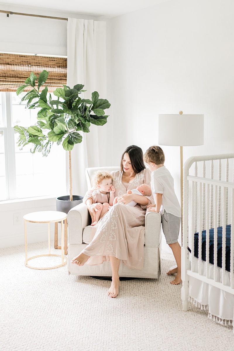 Mama in baby boy's nursery with all of her children. Lifestyle newborn photos by Caitlyn Motycka Photography. 