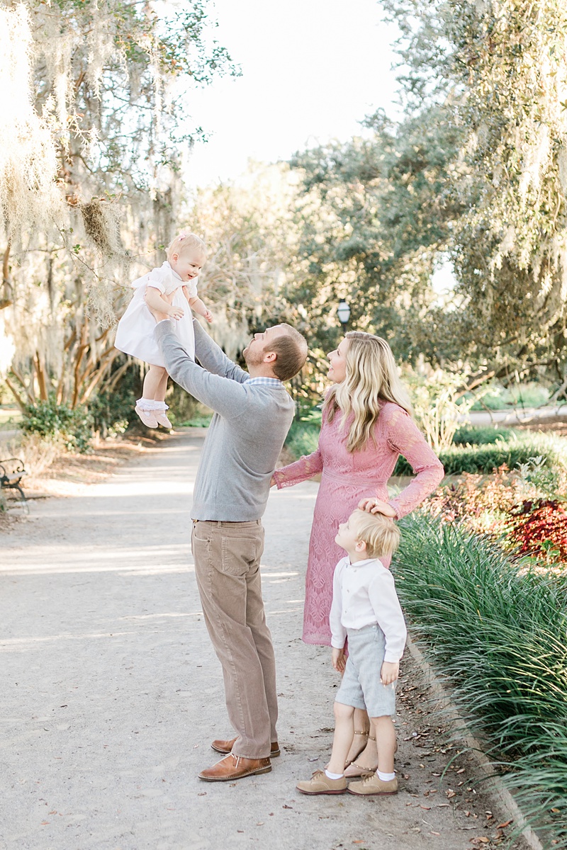 Dad holds little girl up for family photos at sunset fall mini session at Hampton Park. Photos by Charleston Family Photographer, Caitlyn Motycka Photography. 