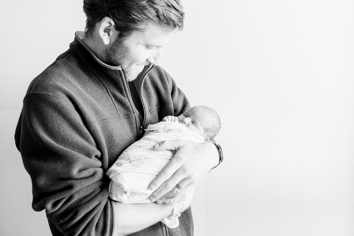 Black and white photo of Dad with his first-born son in the hospital. Photos by Charleston Newborn Photographer, Caitlyn Motycka Photography.