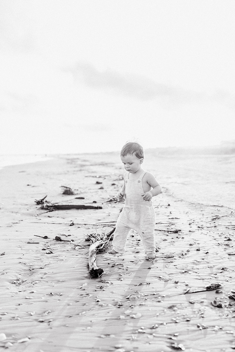 Black and white image of toddler during sunset at the beach by Caitlyn Motycka Photography