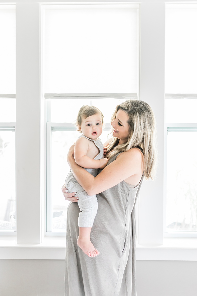 Mom holding toddler on bump during In-home lifestyle maternity session by Caitlyn Motycka Photography