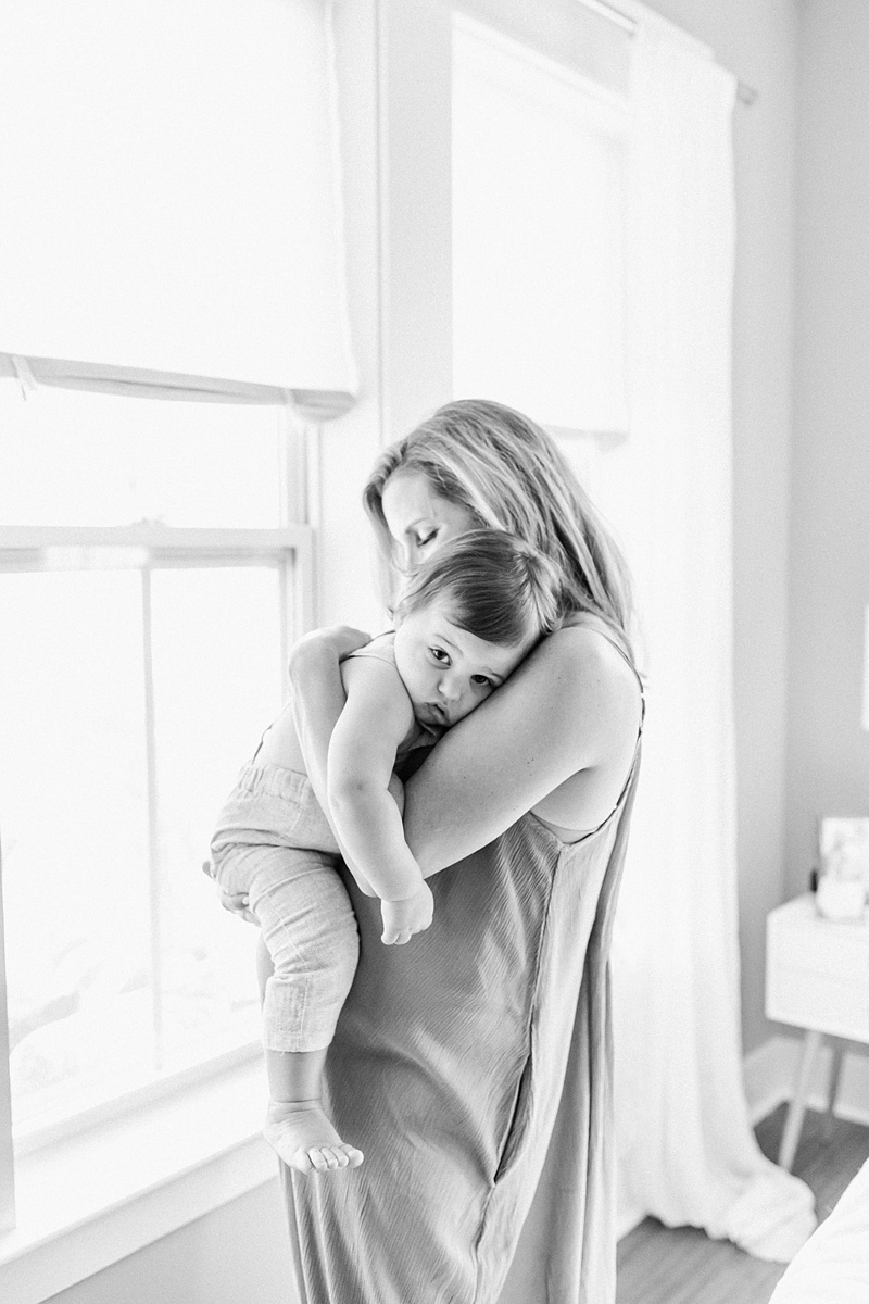 Black and white image of mom cuddling toddler during In-home lifestyle maternity session by Caitlyn Motycka Photography