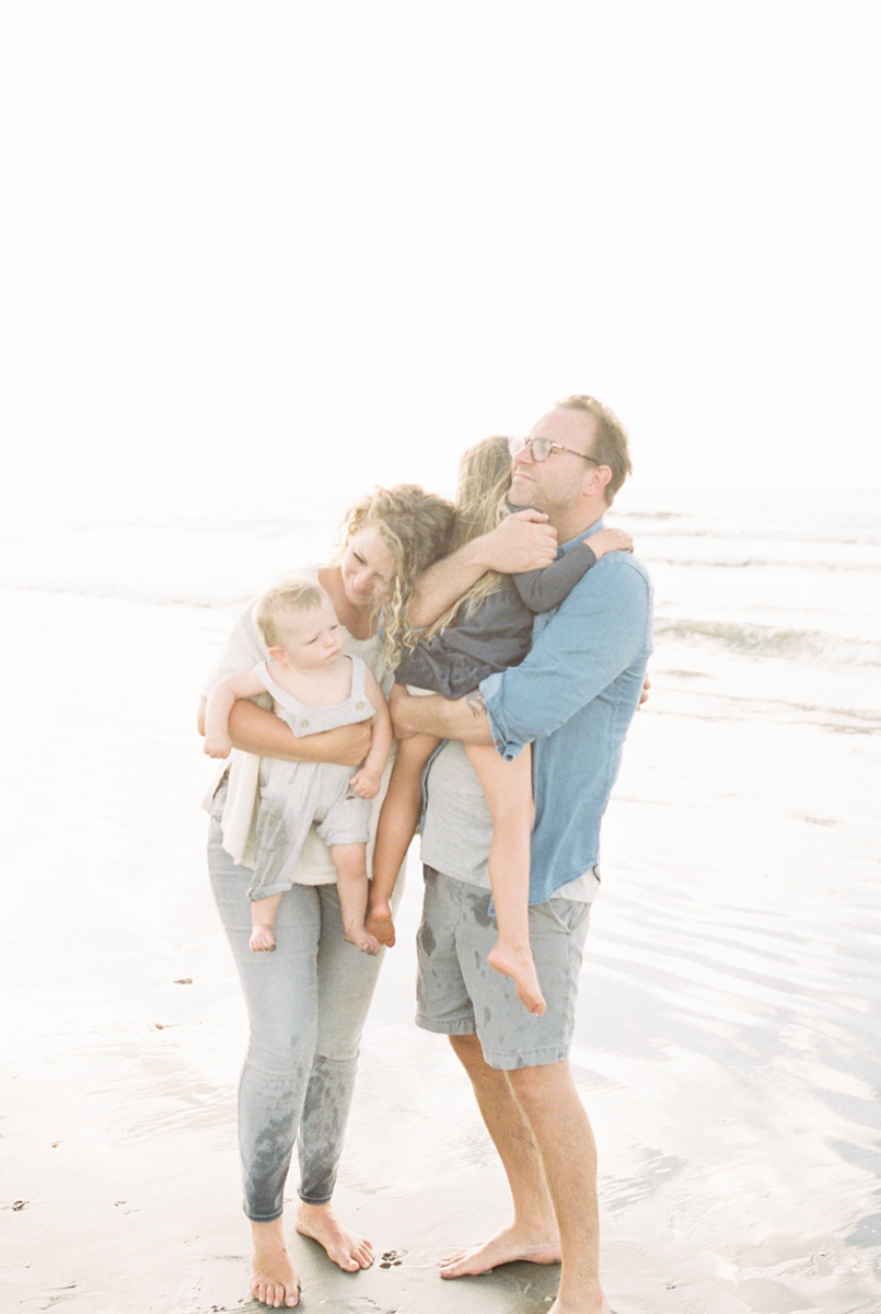 Family embracing each other during sunrise photoshoot at Folly Beach. Photos by Caitlyn Motycka Photography.
