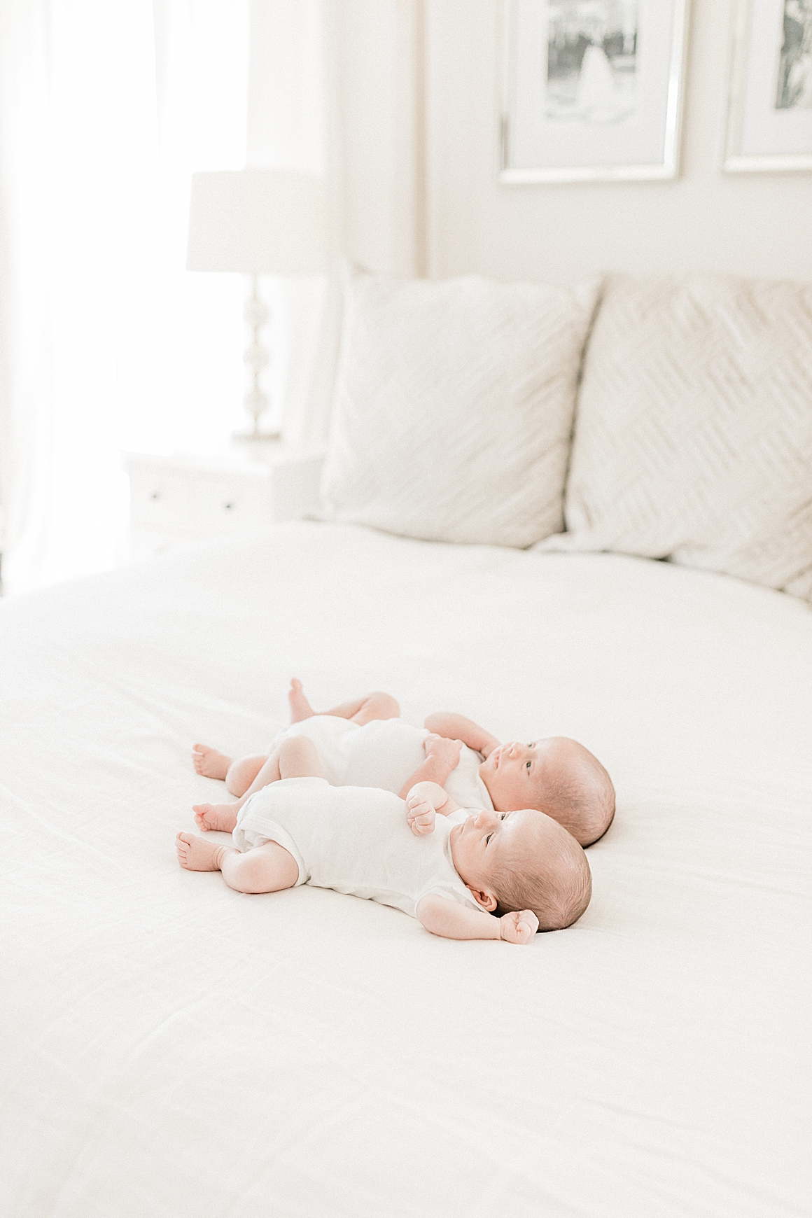 Twin boys laying on bed during lifestyle newborn session in Charleston, SC. Photos by Caitlyn Motycka Photography.