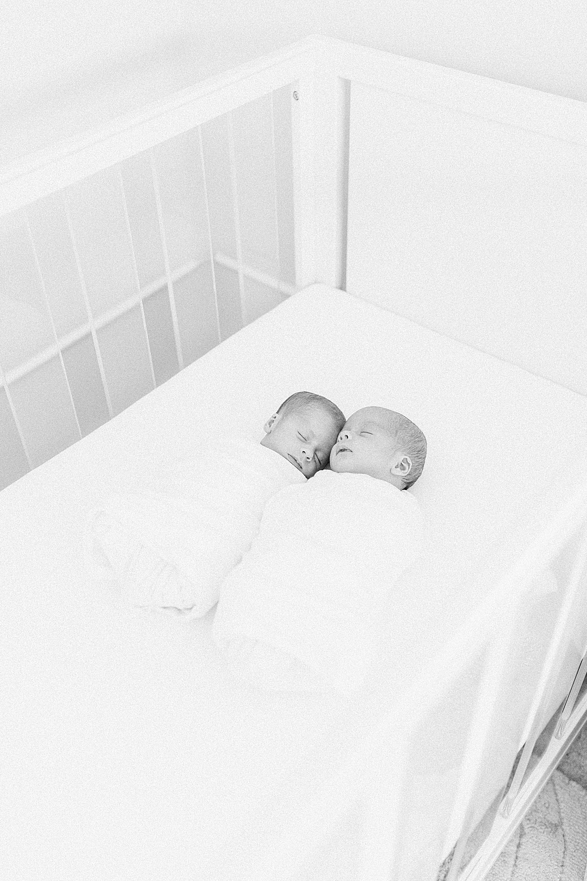 Baby boys laying in crib together in beautiful nursery. Photos by Charleston Newborn Photographer, Caitlyn Motycka Photography.