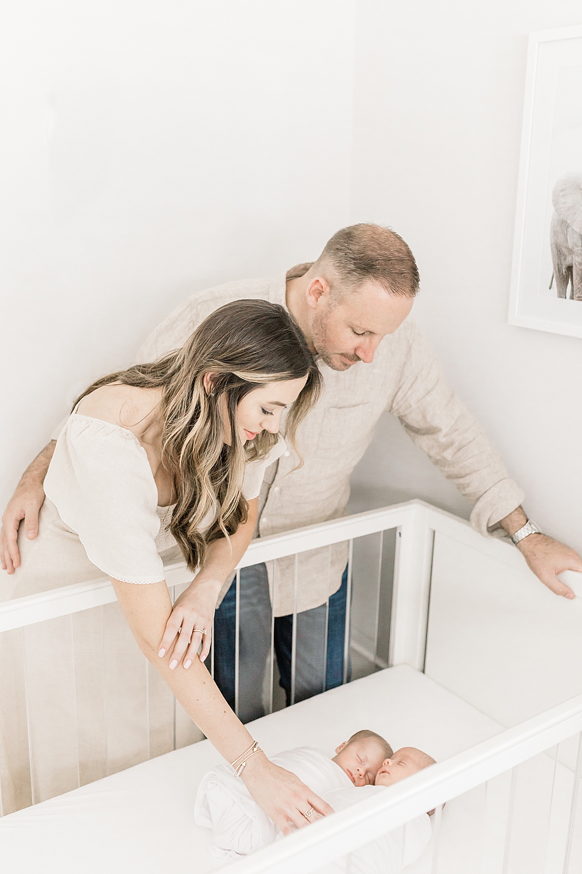 Mom and Dad looking over twin boys in crib during lifestyle newborn session in Charleston, SC. Photos by Caitlyn Motycka Photography.