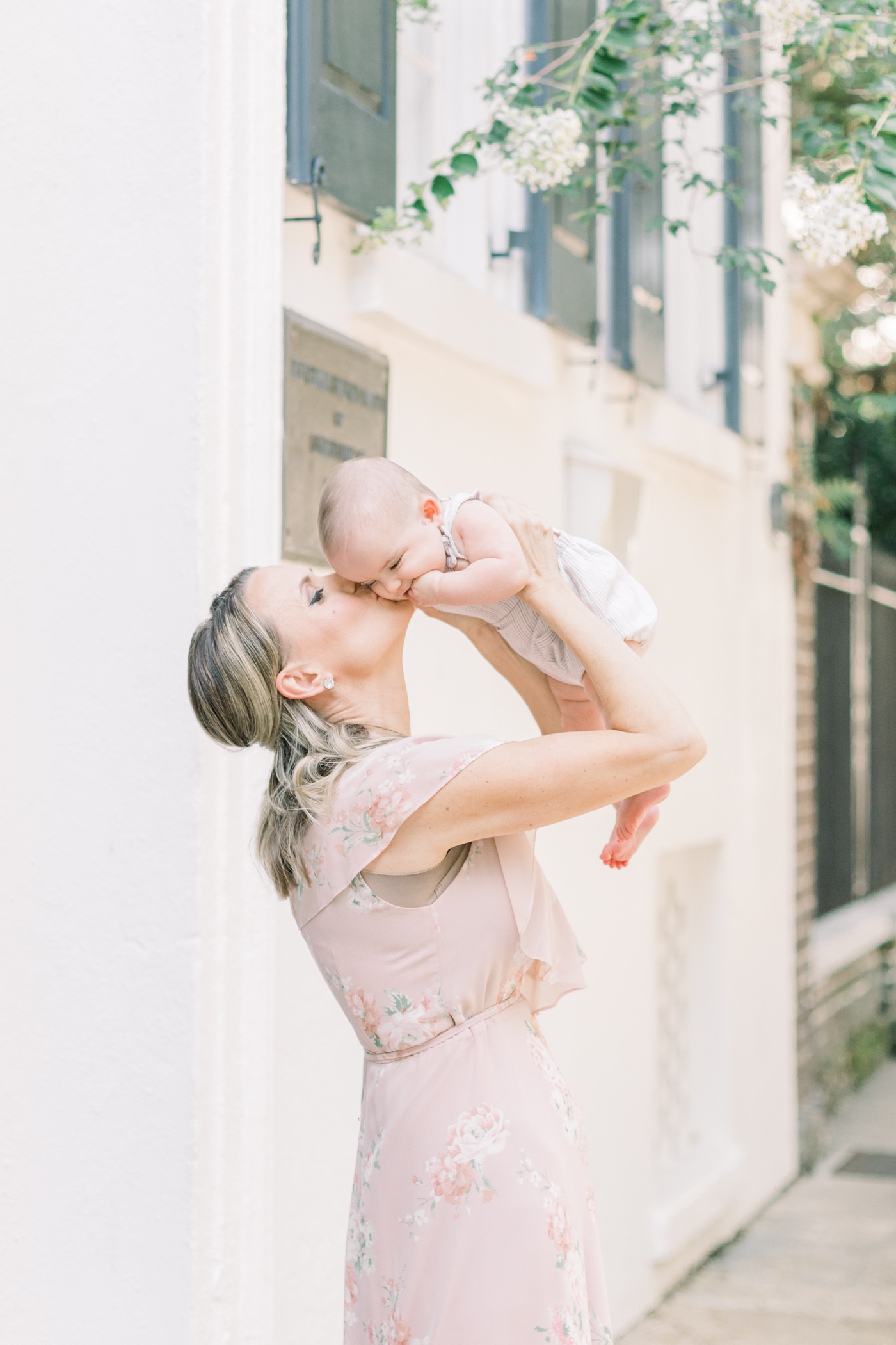 Mom playing airplane with and kissing baby in downtown Charleston. Photo by Caitlyn Motycka Photography.