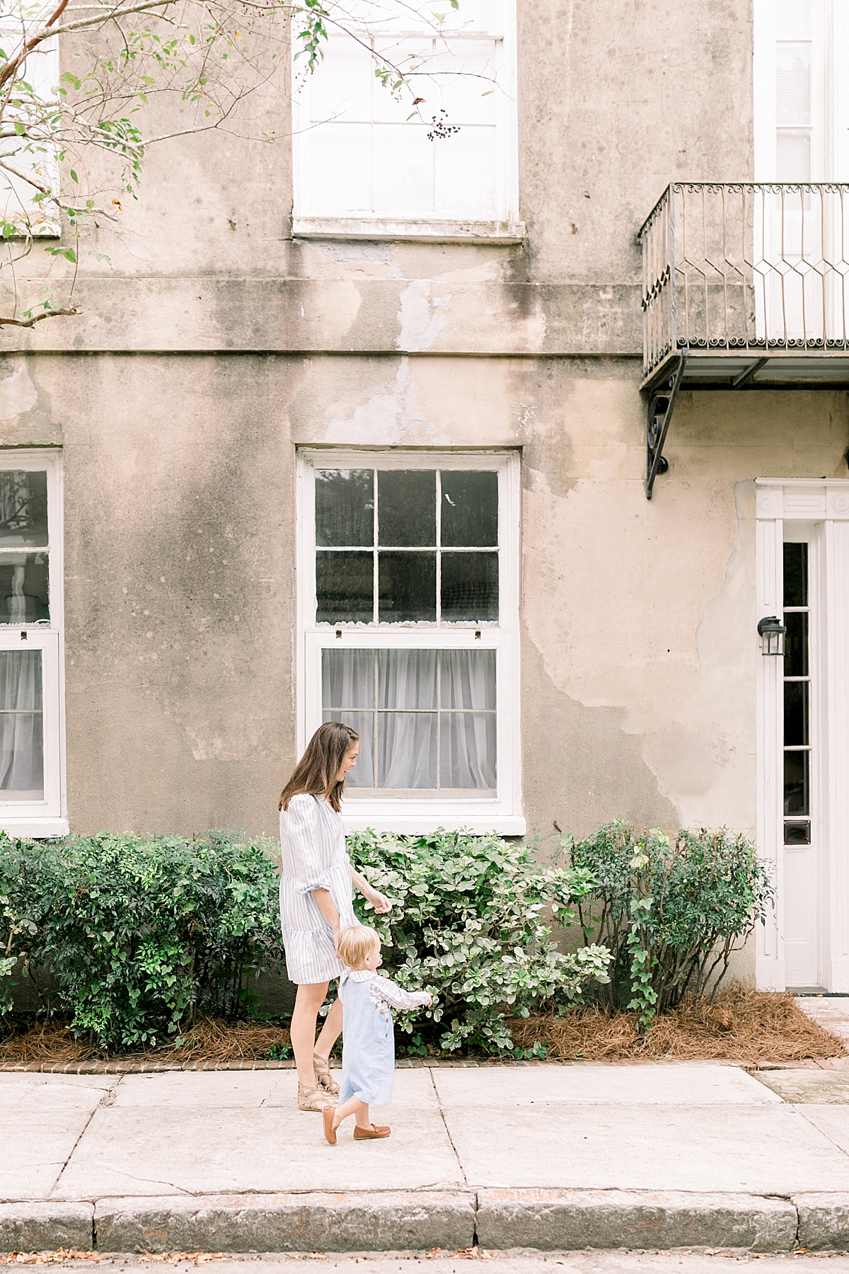 Photo of Mom and son walking together around Downtown Charleston. Family photographer in Charleston photographs family downtown on the cobblestone streets. Photos by Caitlyn Motycka Photography.