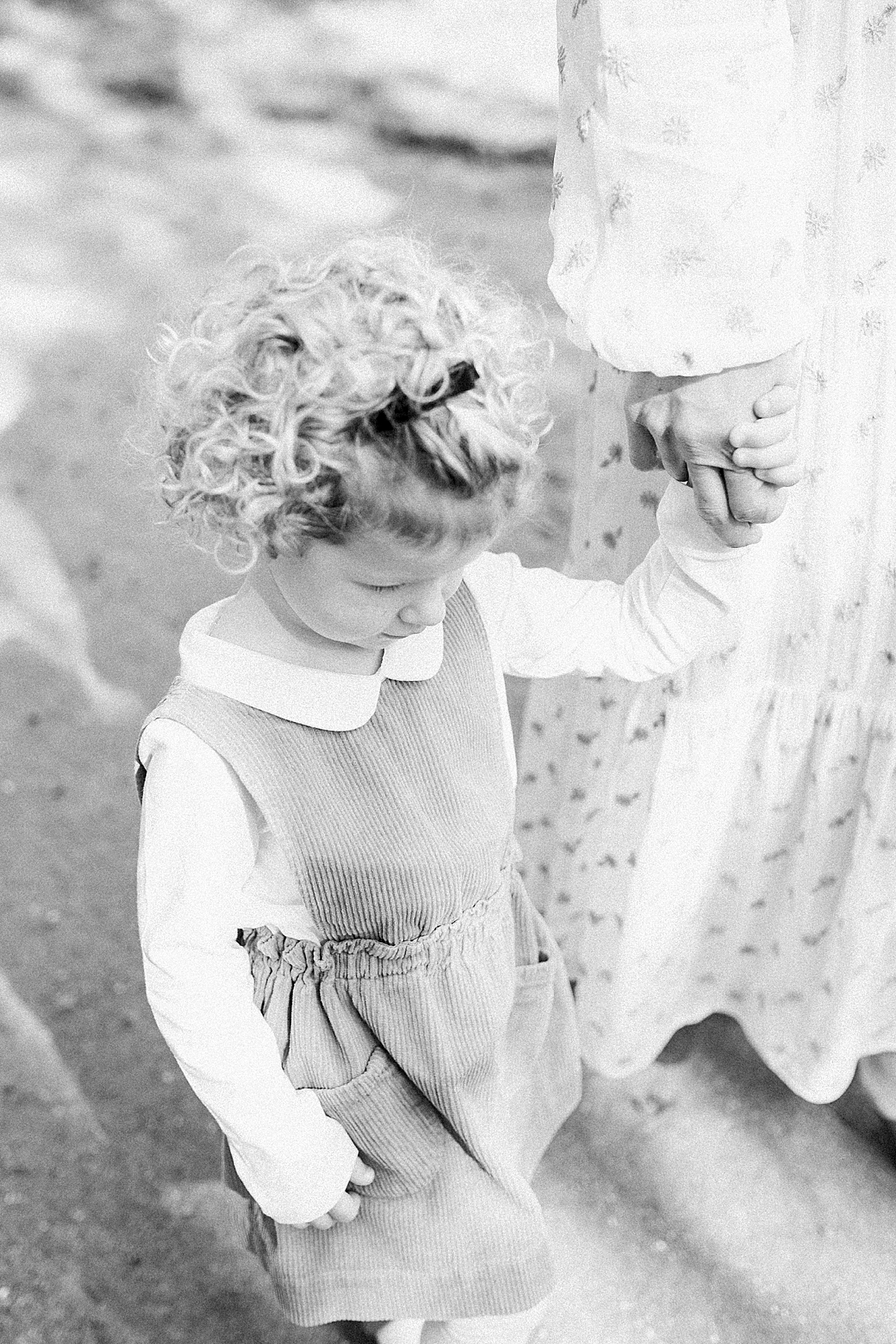 Black and white photo of young girl walking and holding moms hand. Photos by Caitlyn Motycka Photography.