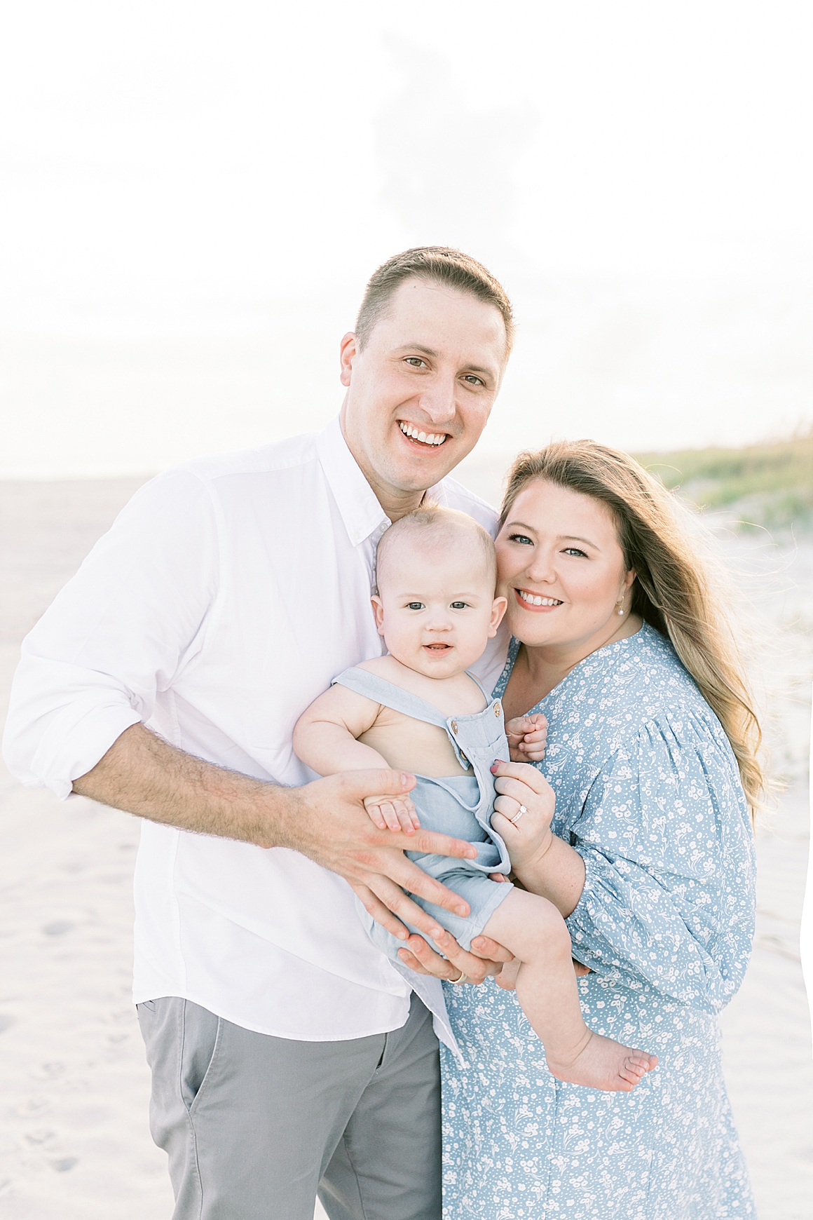 Mom and Dad take photos with their son on the beach for his first birthday. Photos by Caitlyn Motycka Photography.