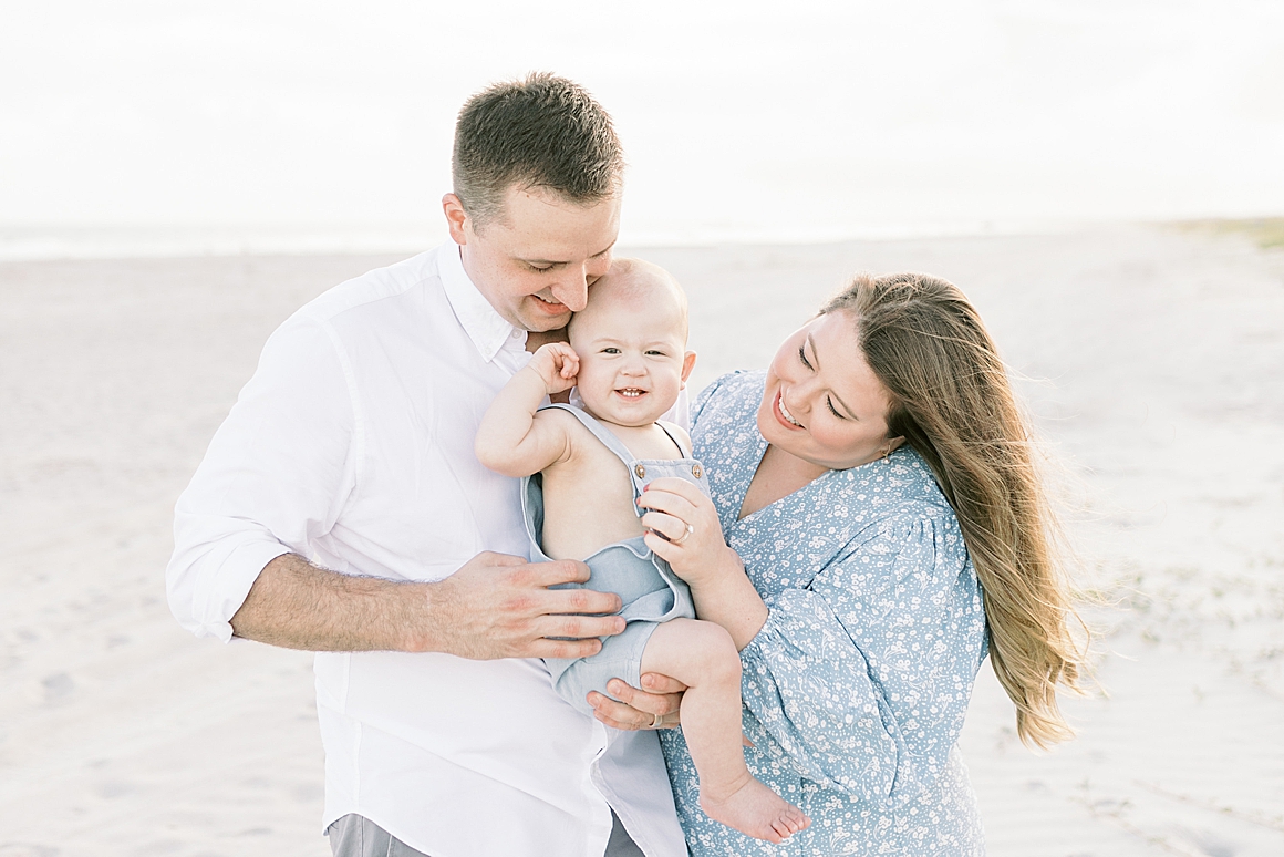 Mom and Dad take photos with their son on the beach for his first birthday. Photos by Caitlyn Motycka Photography.
