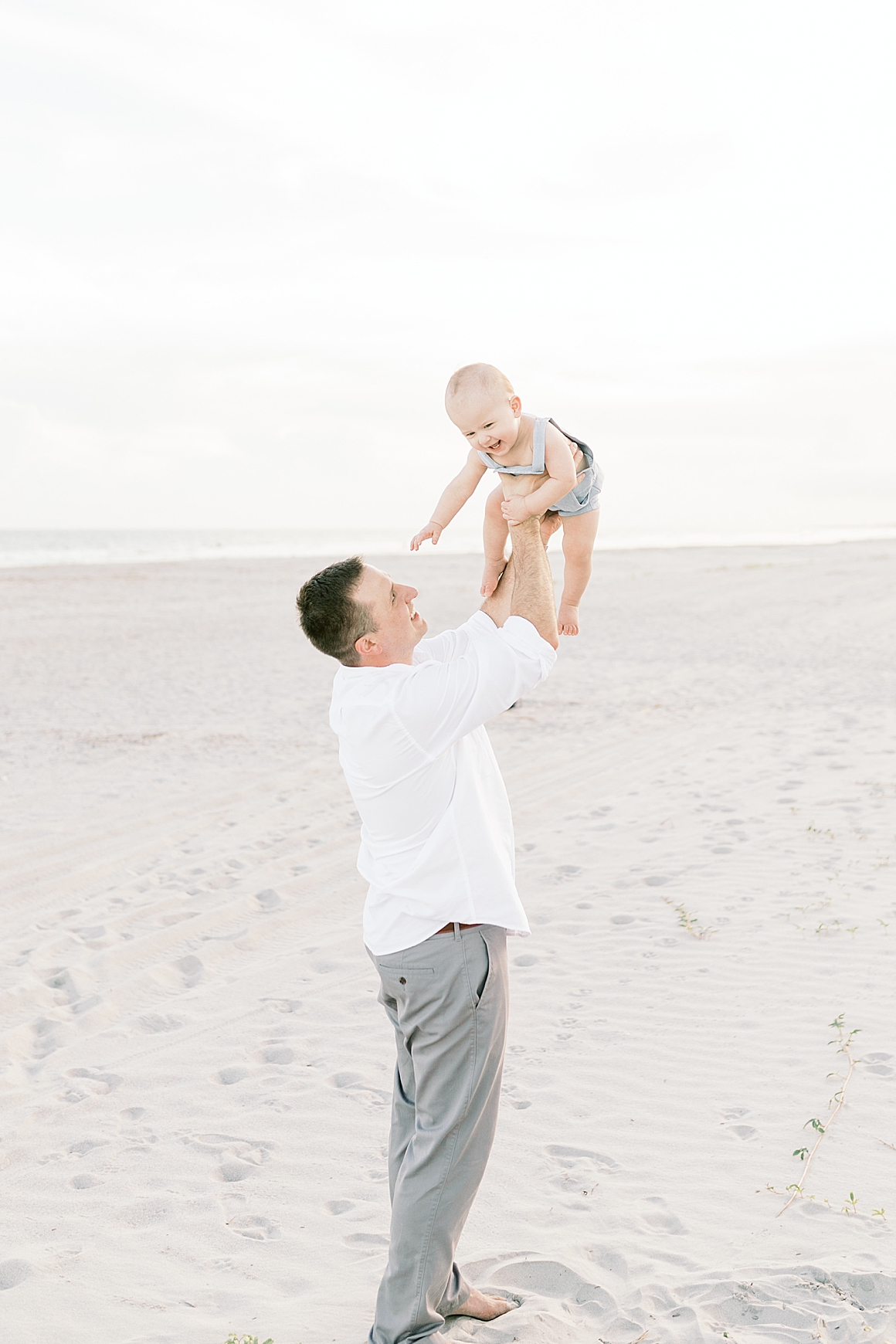 Dad playing airplane with his son during first birthday photoshoot. Photos by Caitlyn Motycka Photography.