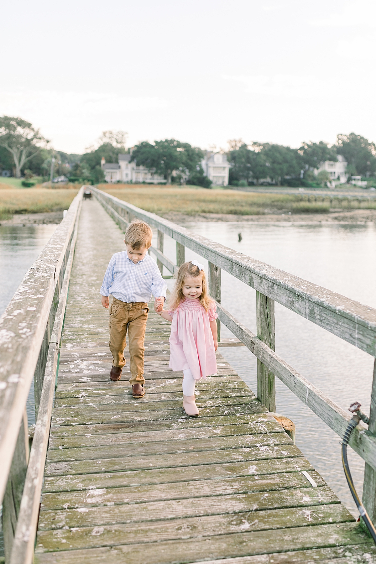 Brother and sister holding hands on family's dock in Old Village Mount Pleasant. Photos by Caitlyn Motycka Photography/