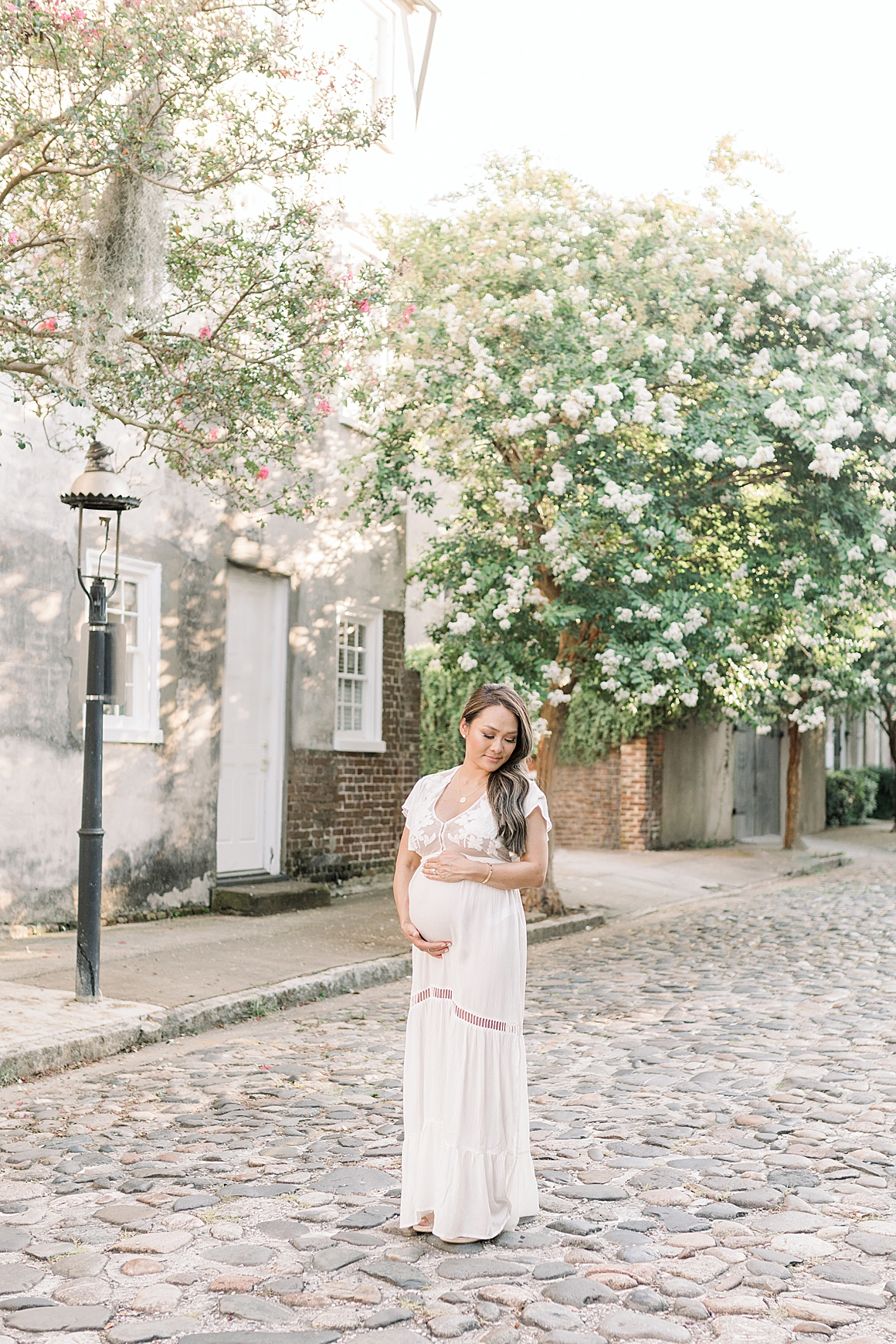 Stunning pregant mama along the cobblestone streets in Downtown Charleston. Photos by Caitlyn Motycka Photography.