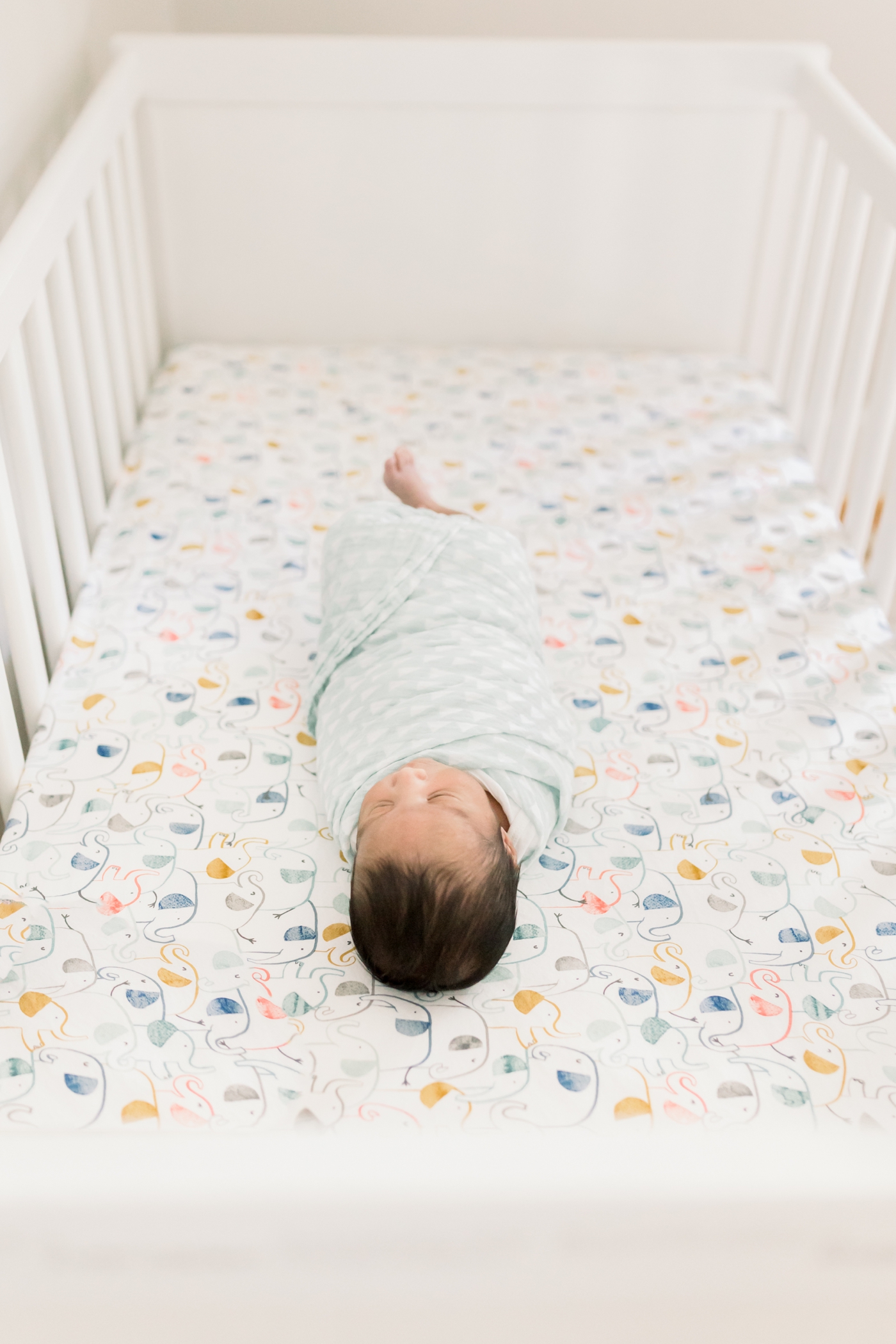 Newborn baby boy laying in crib | Photo by Caitlyn Motycka Photography.