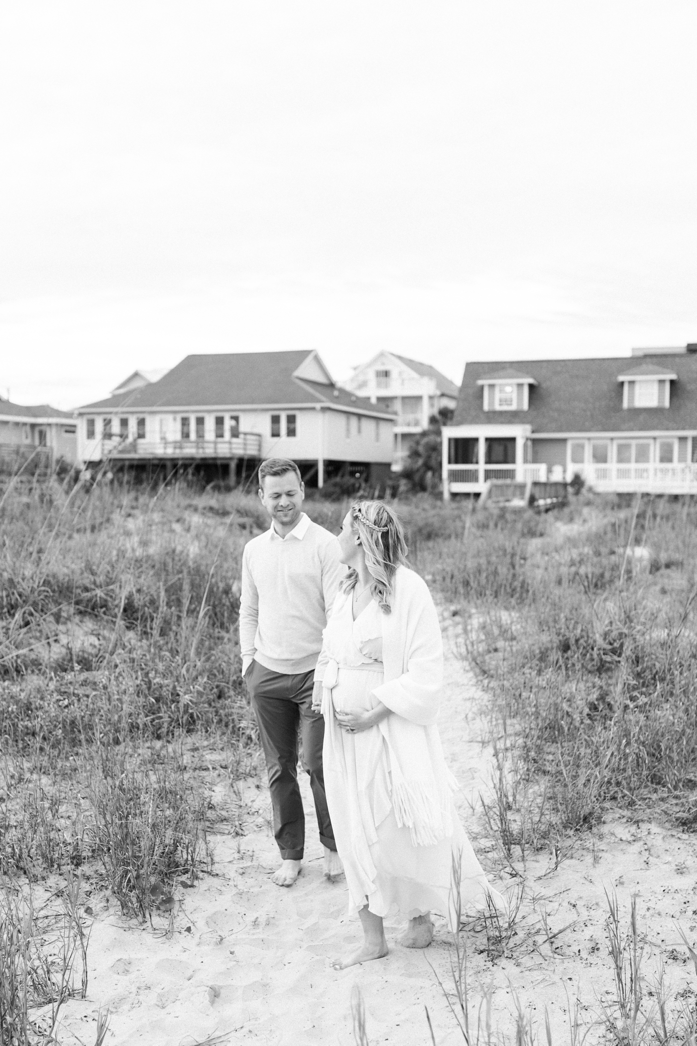 Black and white maternity photo of parents-to-be walking and looking at each other. Photo by Caitlyn Motycka Photography.