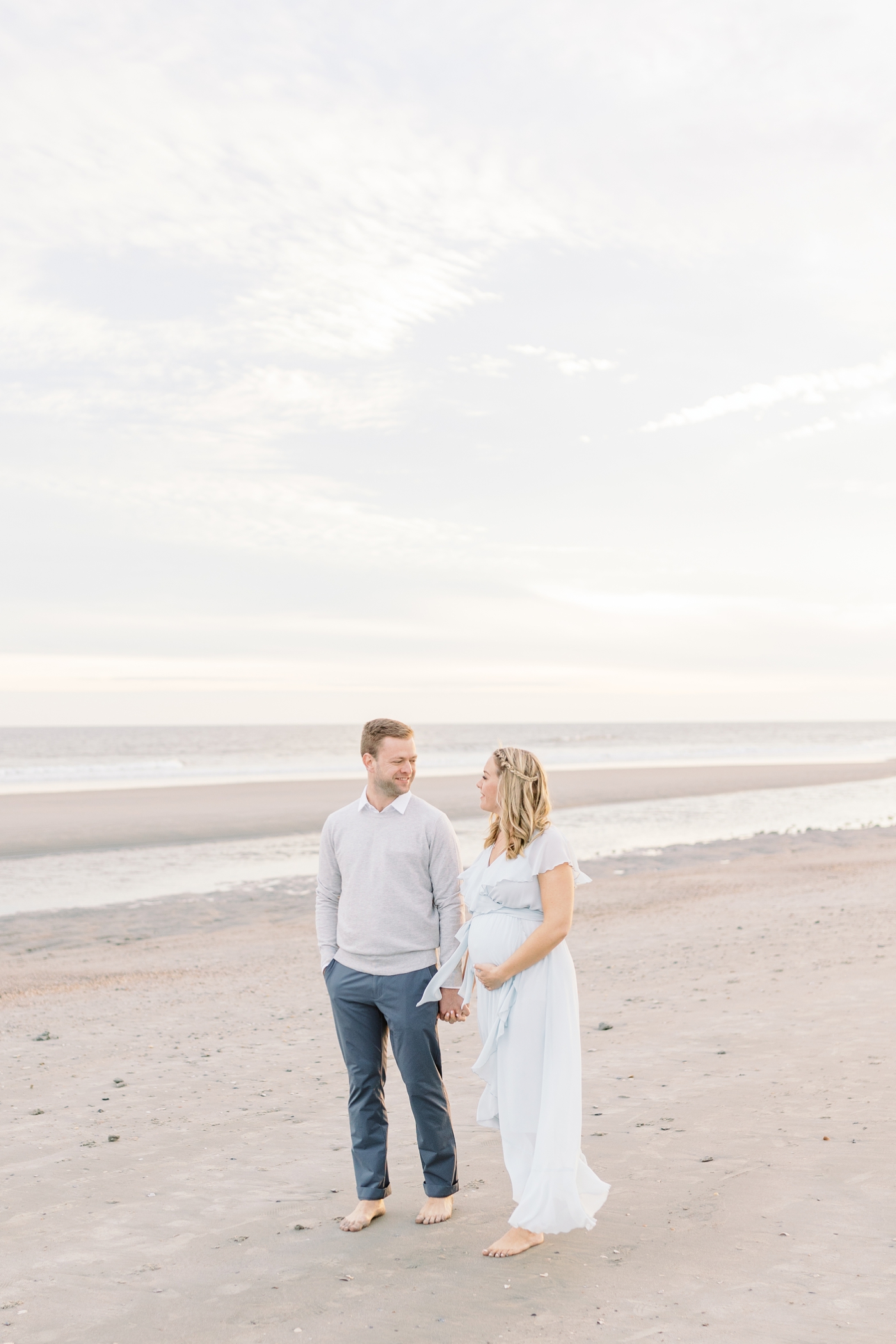 Couple walking on the beach at Folly during babymoon to Charleston. Photo by Caitlyn Motycka Photography.