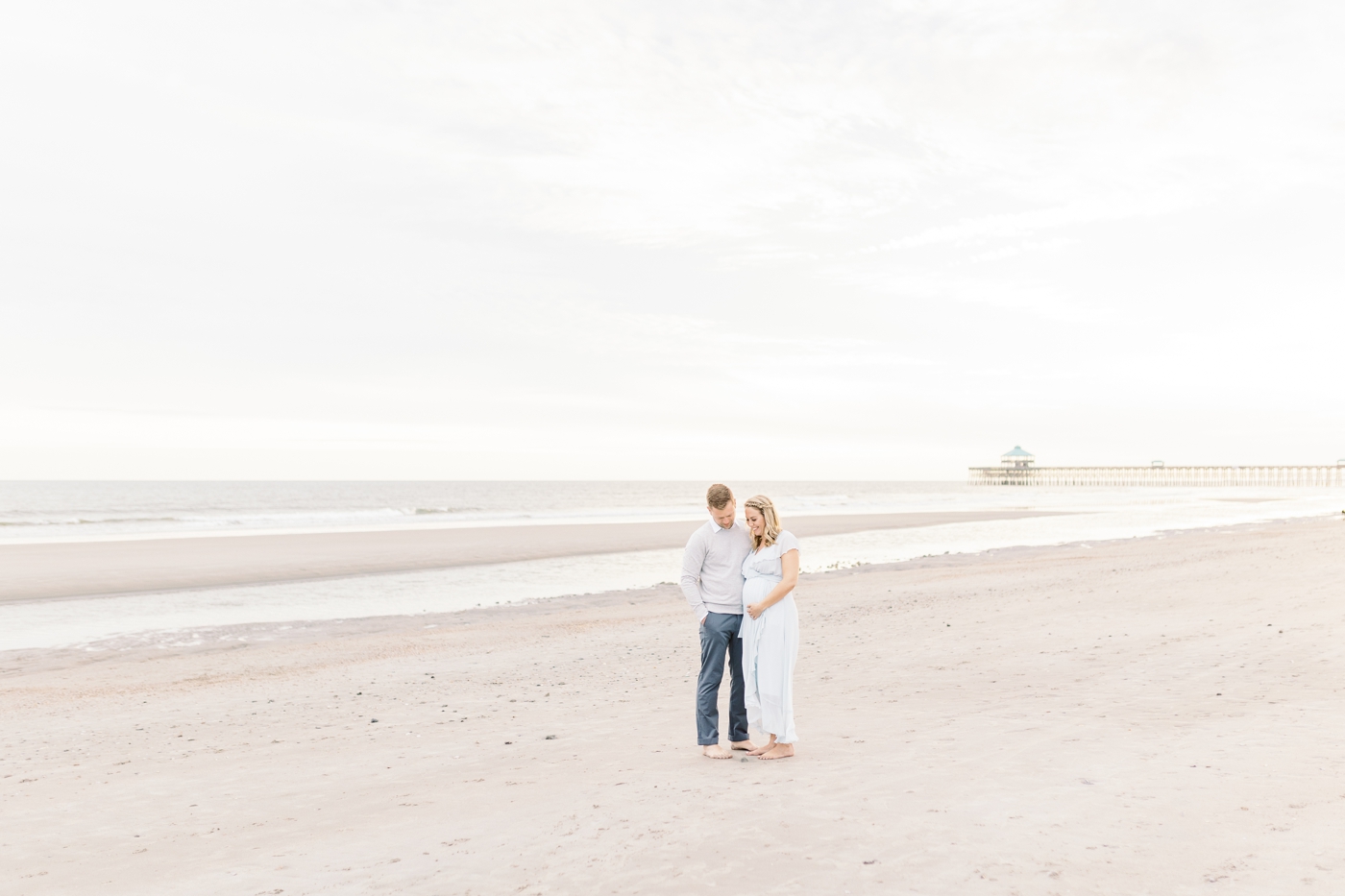Folly Beach maternity photoshoot with the pier in the background. Photo by Caitlyn Motycka Photography.