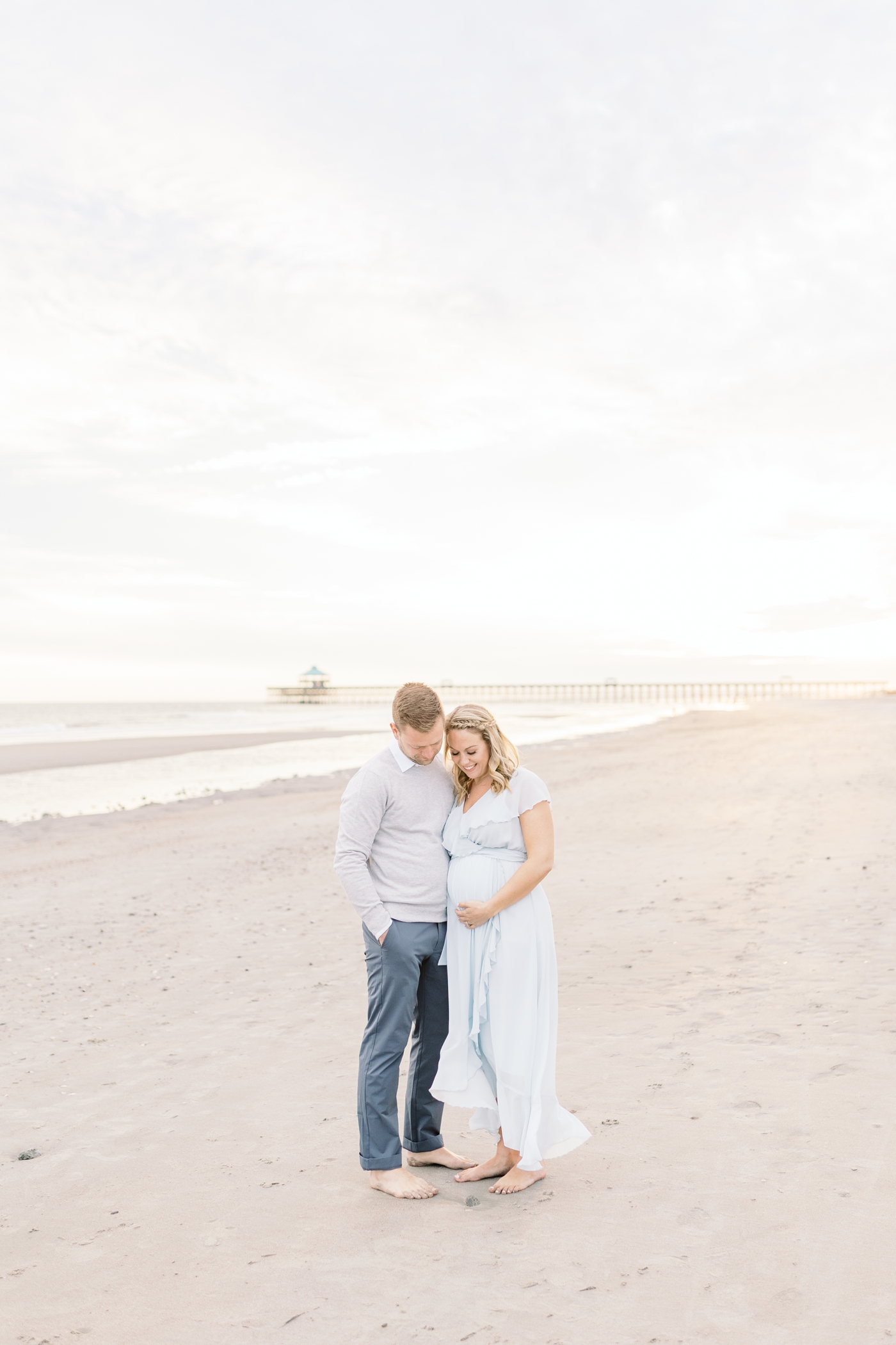 Maternity photoshoot with Folly Beach Pier in the background. Photo by Caitlyn Motycka Photography.