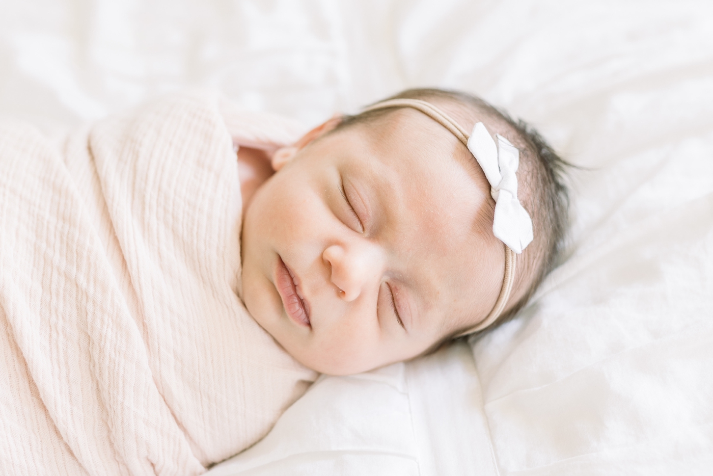Closeup of baby sleeping during newborn session with light pink swaddle blanket. Photo by Caitlyn Motycka Photography.