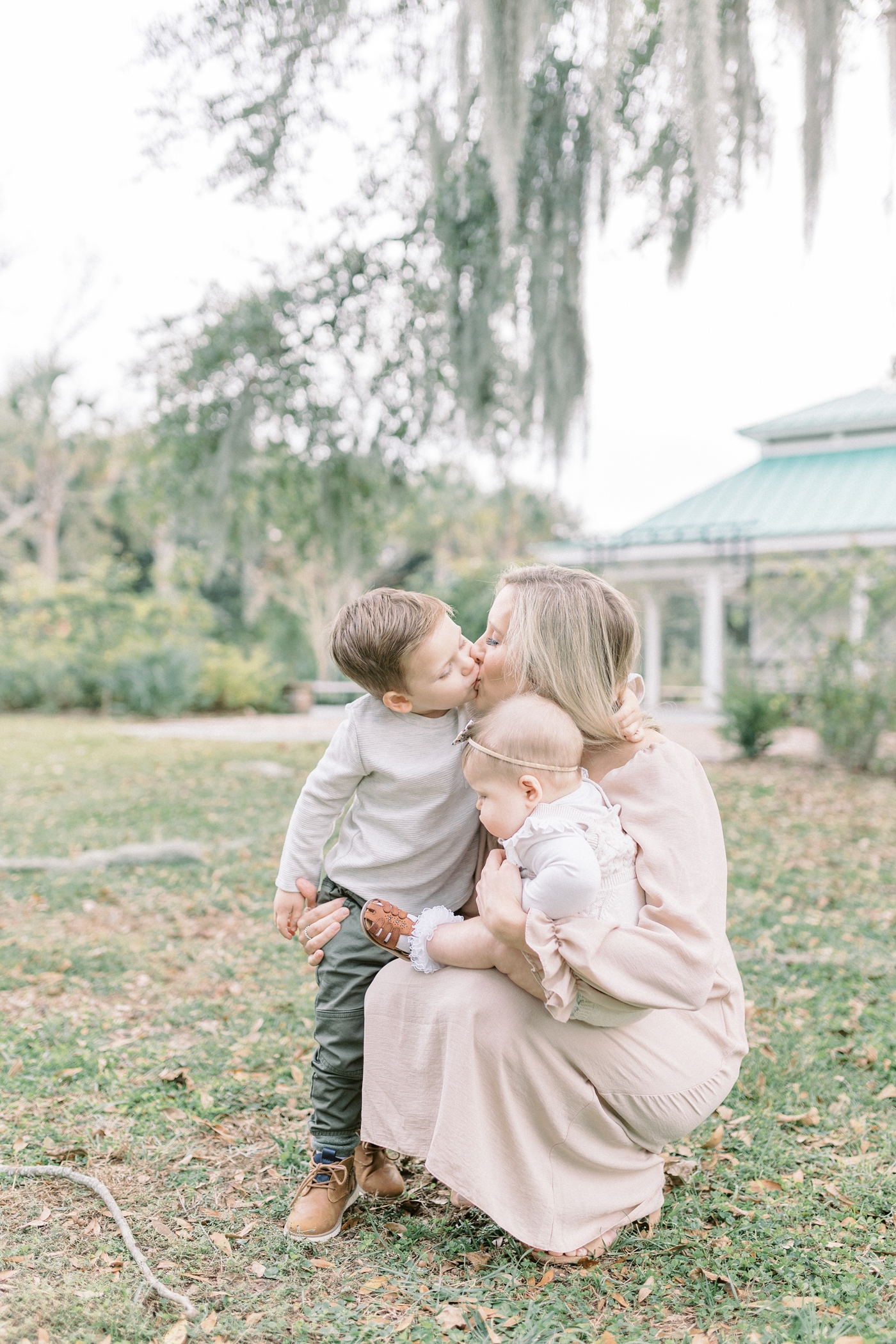 Toddler giving Mom a kiss during family session surrounded by Spanish moss.Photo by Caitlyn Motycka Photography.
