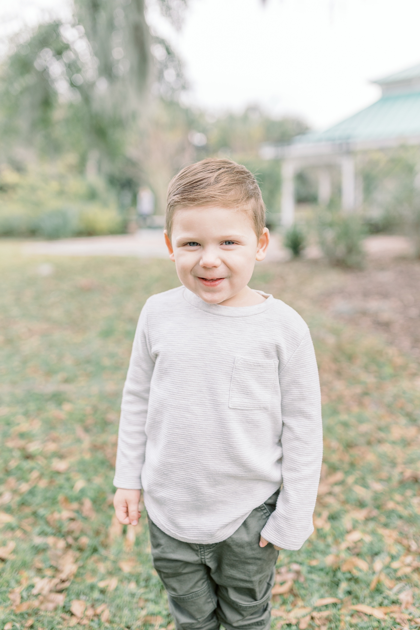 Toddler boy smiling at the camera during overcast park family session. Photo by Caitlyn Motycka Photography.