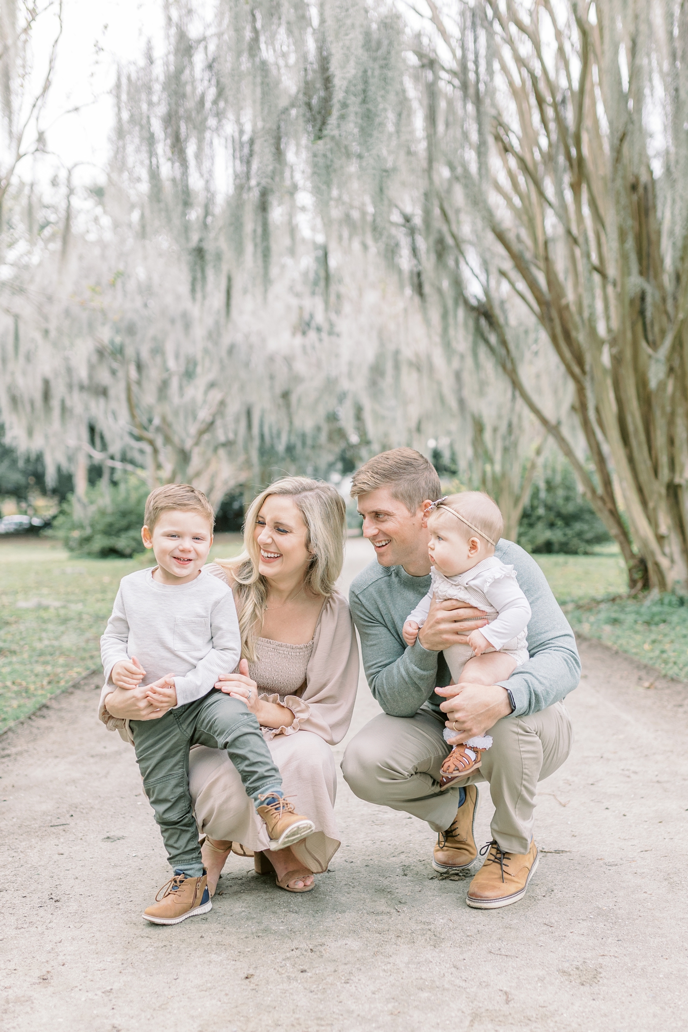 Family of four smiling at toddler during session. Photo by Caitlyn Motycka Photography.