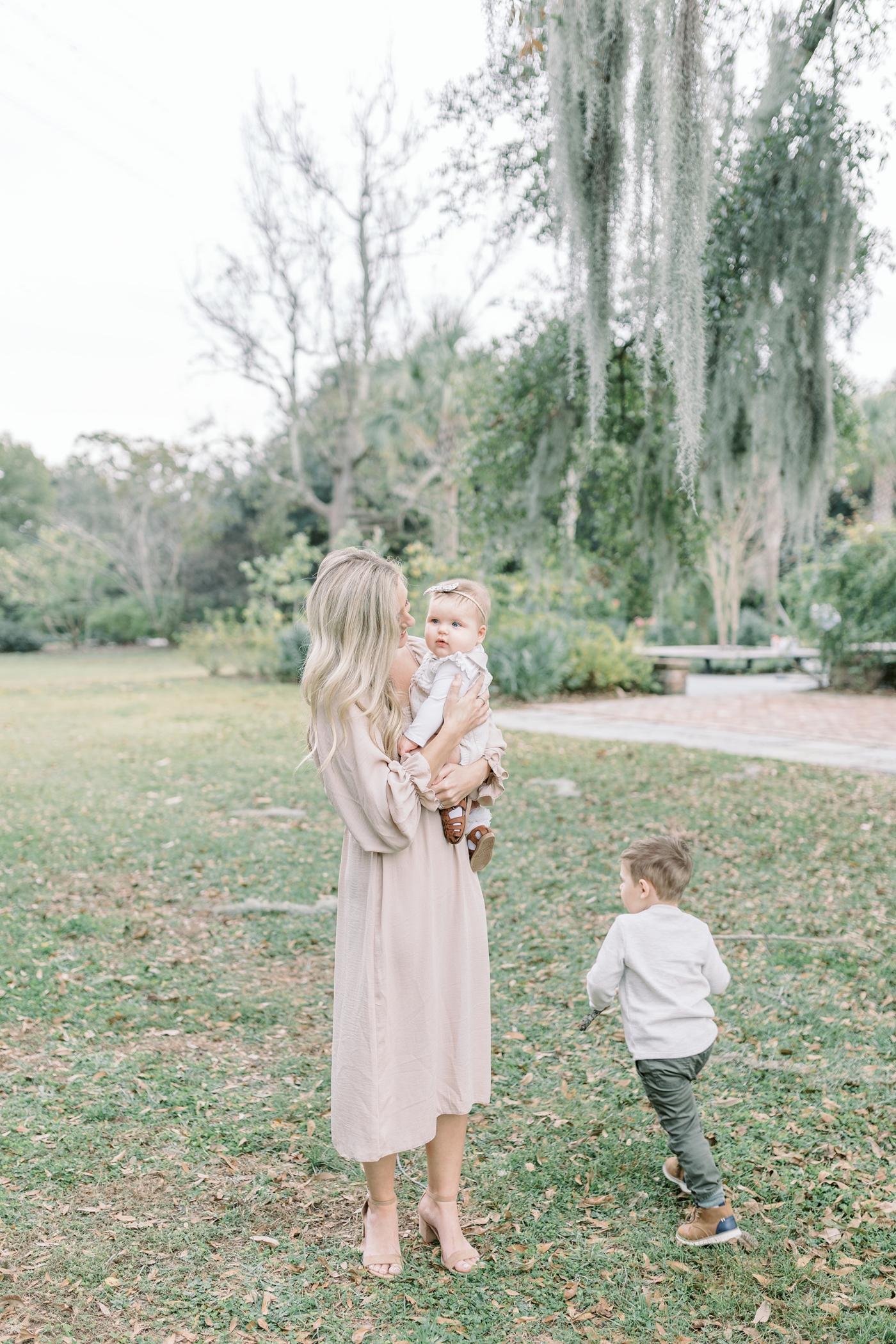 Mom holding baby while big brother plays next to them. Photo by Charleston SC family photographer, Caitlyn Motycka Photography.
