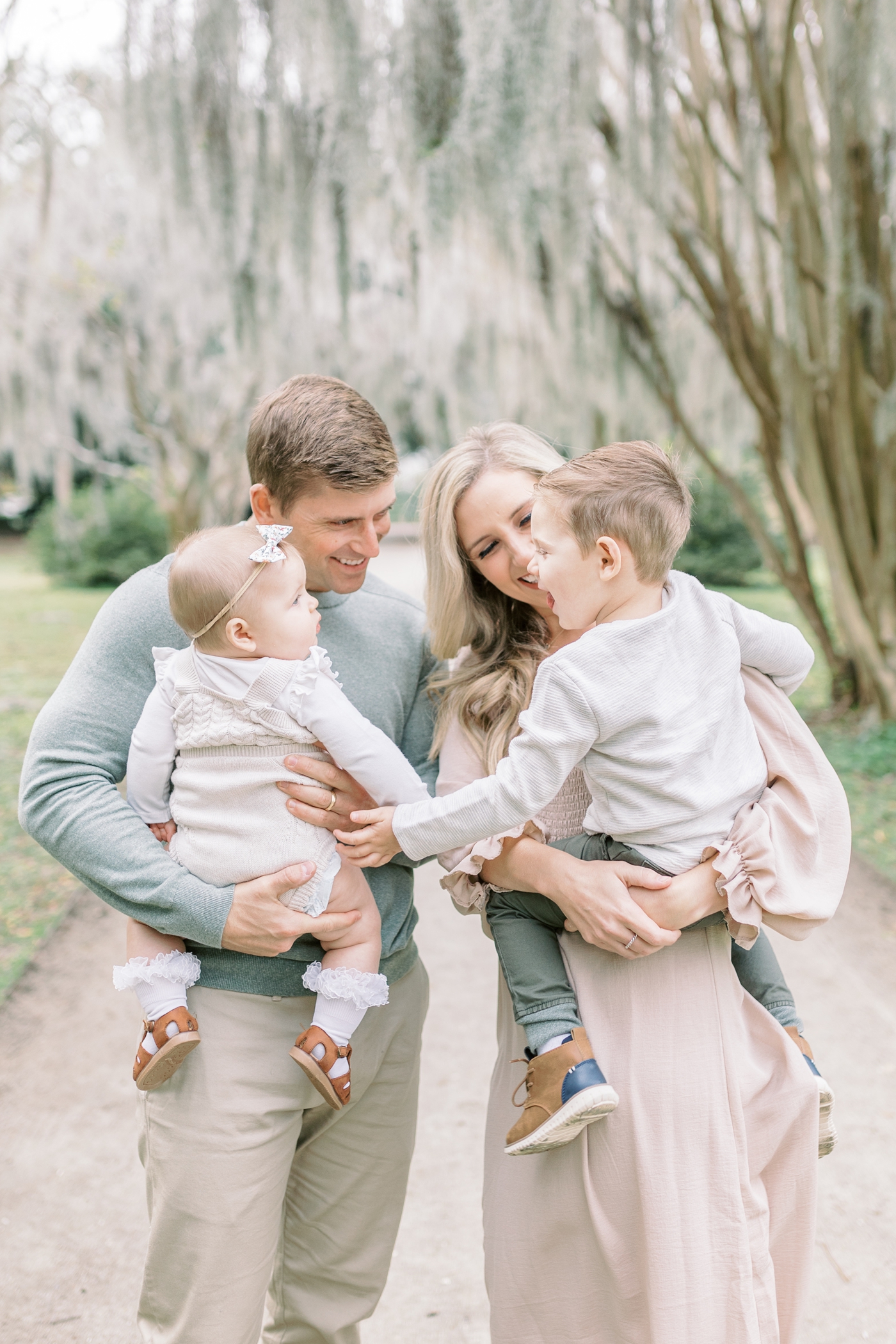 Parents smiling at two children and surrounded by Spanish moss at Hampton Park. Photo by Charleston SC family photographer, Caitlyn Motycka Photography.