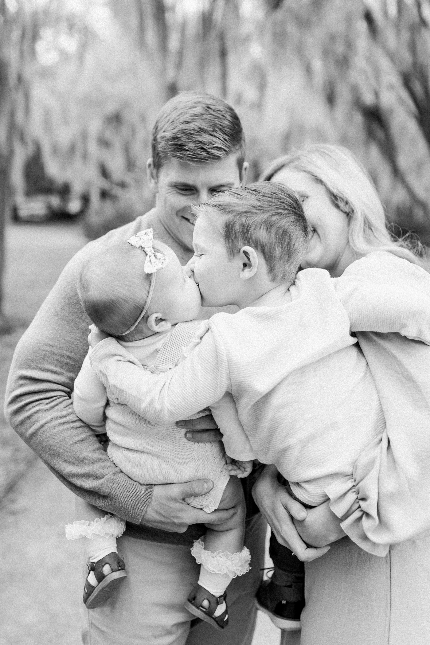 Black and white image of big brother giving baby a kiss. Photo by Caitlyn Motycka Photography.